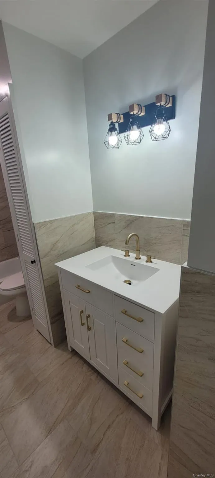 Bathroom with vanity, toilet, and tile walls Bathroom with vanity, toilet, and tile walls