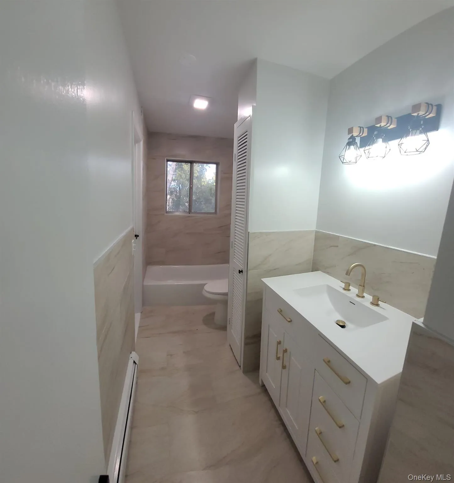 Bathroom with vanity, a baseboard radiator, tile walls, tile patterned flooring, and toilet Bathroom with vanity, a baseboard radiator, tile walls, tile patterned flooring, and toilet