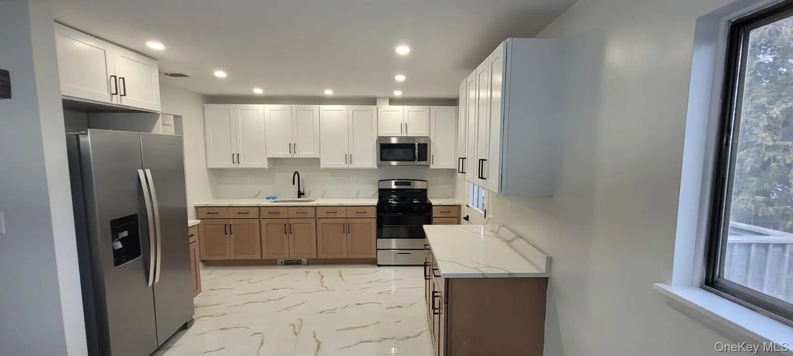 Kitchen with light stone counters, sink, white cabinets, and appliances with stainless steel finishes Kitchen with light stone counters, sink, white cabinets, and appliances with stainless steel finishes