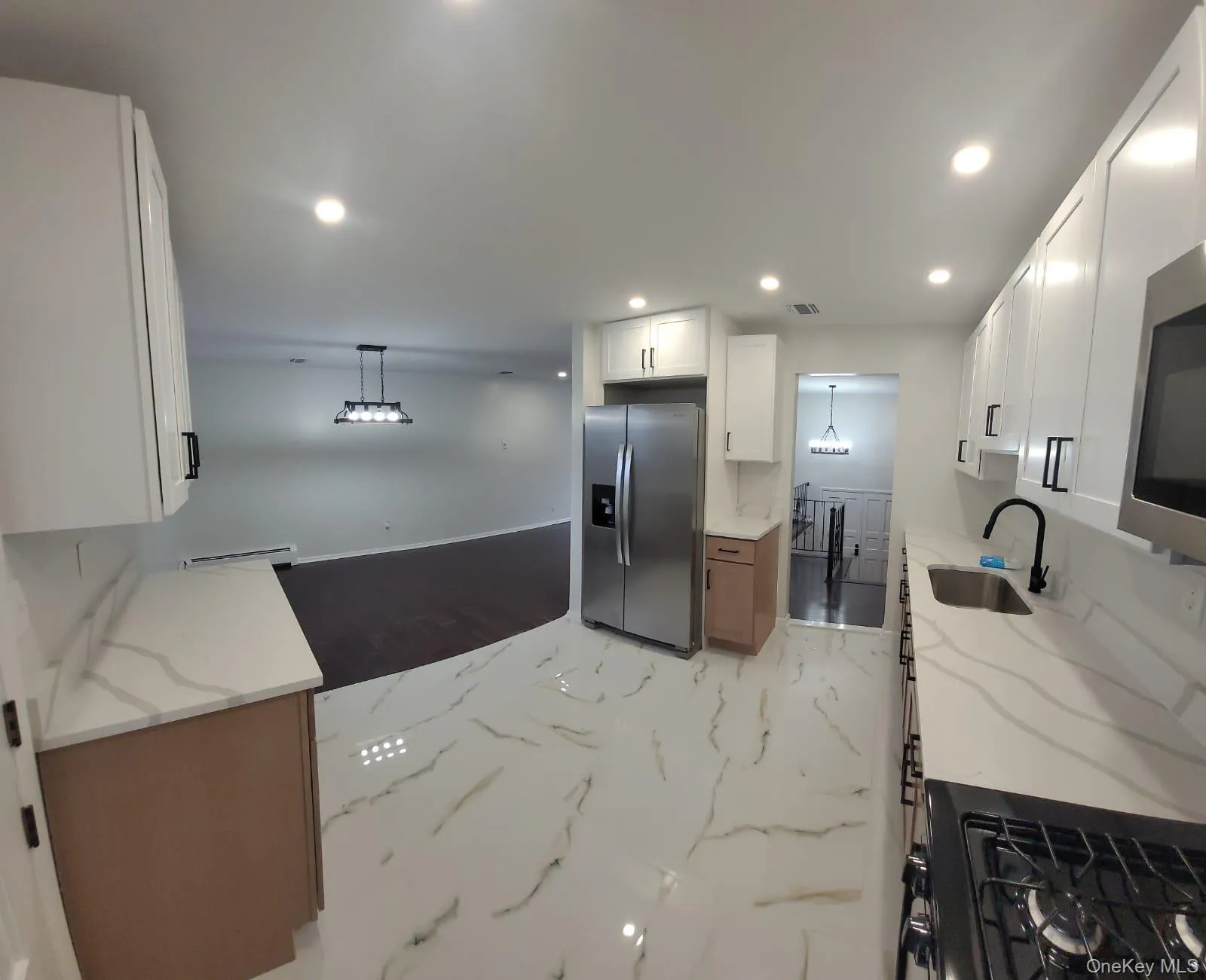 Kitchen featuring white cabinets, sink, light stone countertops, appliances with stainless steel finishes, and decorative light fixtures Kitchen featuring white cabinets, sink, light stone countertops, appliances with stainless steel finishes, and decorative light fixtures