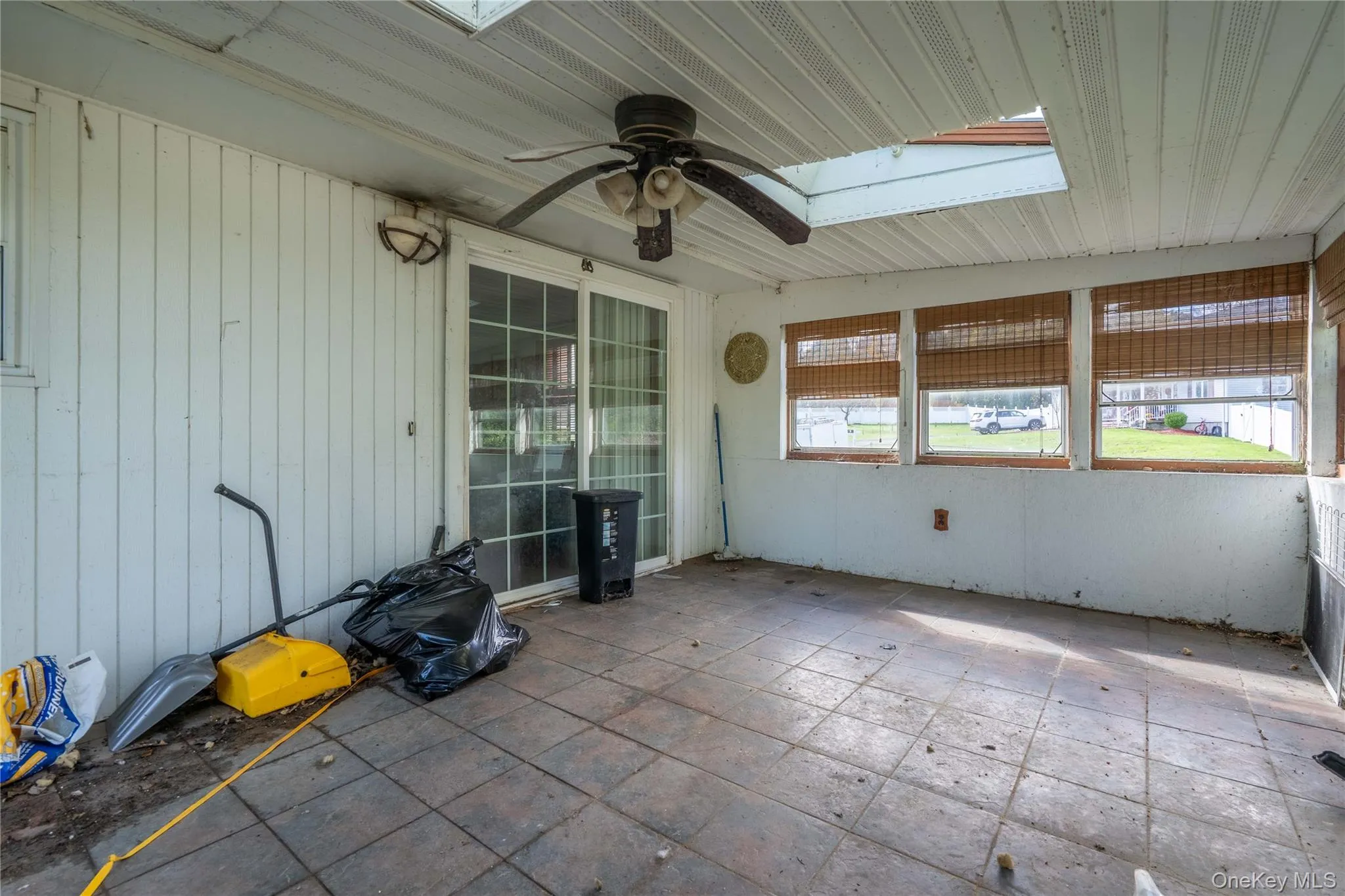 Enclosed patio featuring tile flooring, a skylight, a ceiling fan, and sliding glass doors Enclosed patio featuring tile flooring, a skylight, a ceiling fan, and sliding glass doors