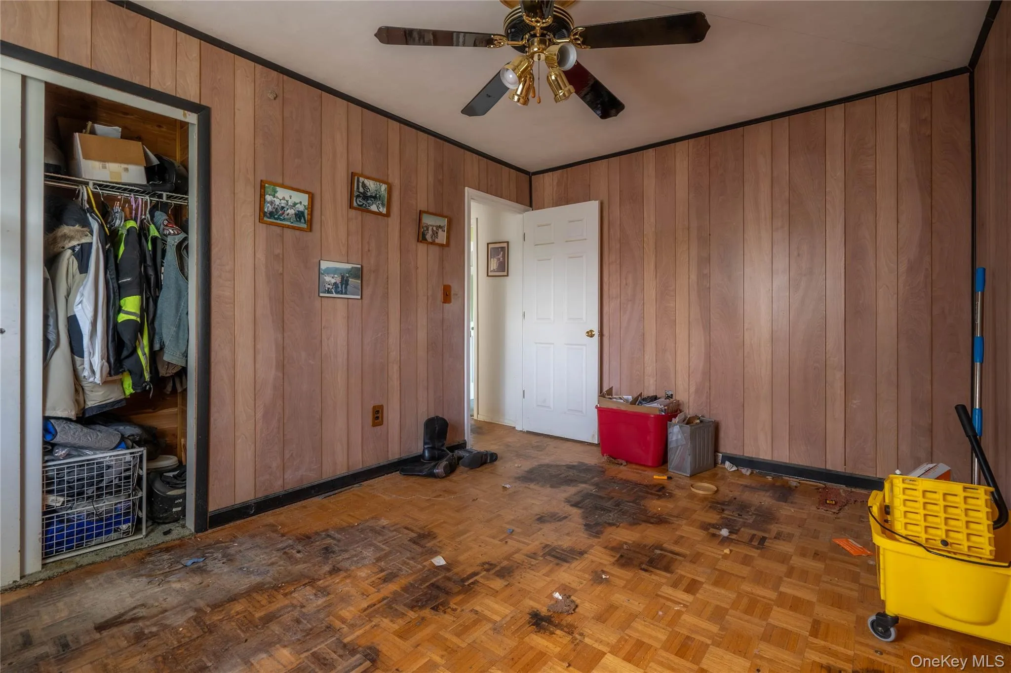 Wood-panelled wall treatments, parquet flooring, and a ceiling-mounted fan with integrated lighting Wood-panelled wall treatments, parquet flooring, and a ceiling-mounted fan with integrated lighting