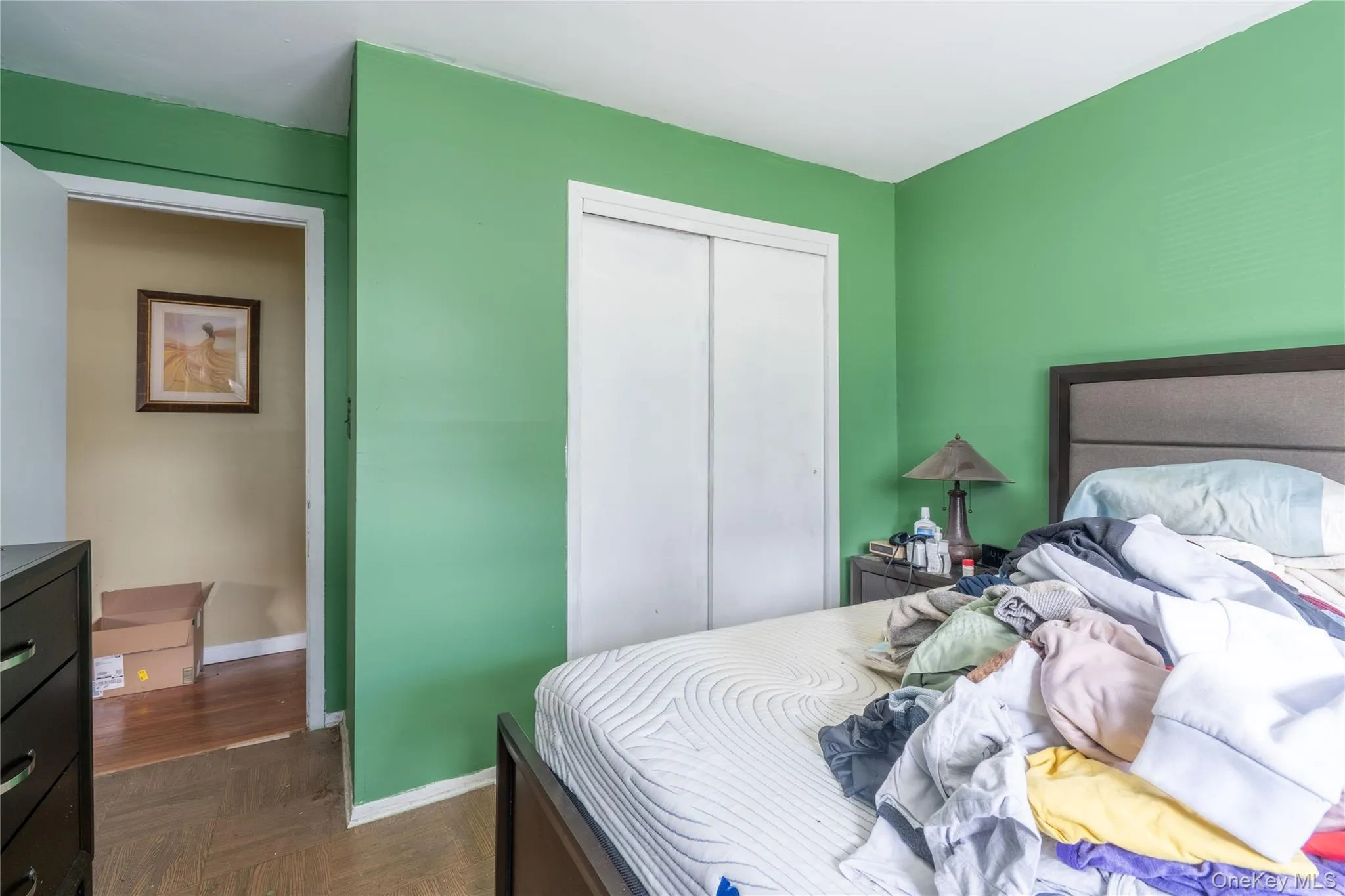 Interior room featuring parquet wood-finish flooring and a closet with white sliding doors Interior room featuring parquet wood-finish flooring and a closet with white sliding doors