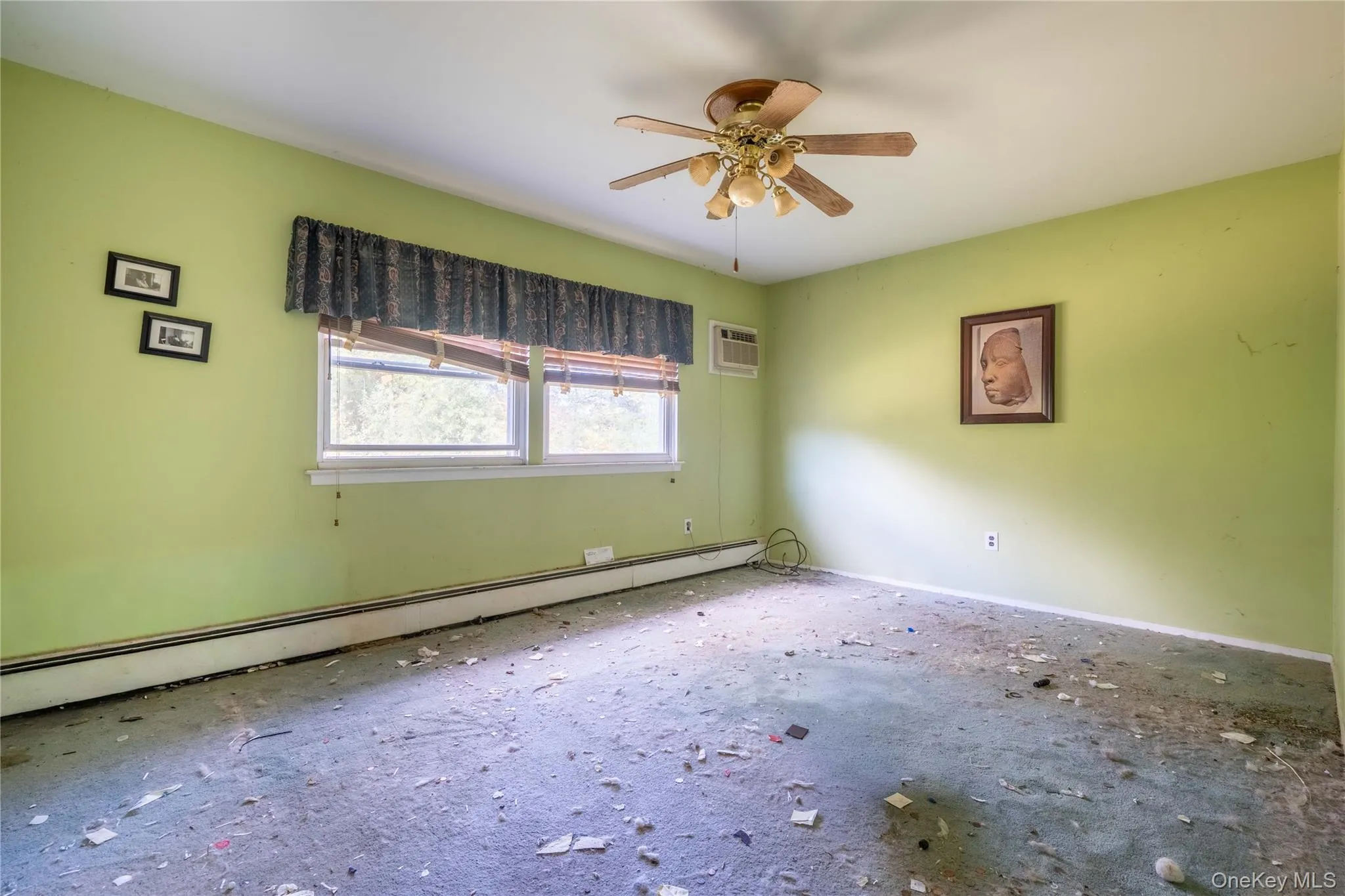 Interior room featuring double-pane windows, a ceiling-mounted light fixture with a five-blade fan, and a wall-mounted climate control unit Interior room featuring double-pane windows, a ceiling-mounted light fixture with a five-blade fan, and a wall-mounted climate control unit