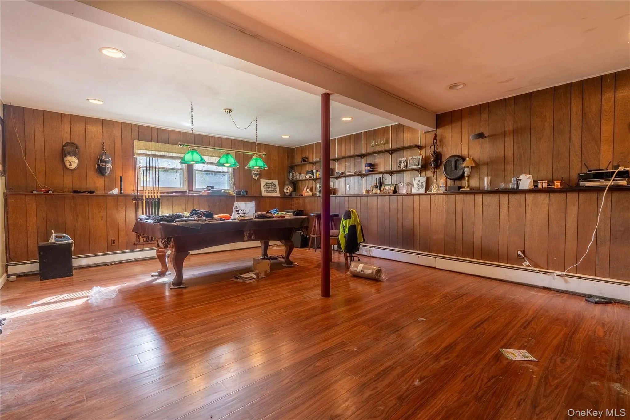 Wood-paneled wall treatments, wood-finish flooring, recessed ceiling lighting, three-light hanging fixture, and built-in wall shelving Wood-paneled wall treatments, wood-finish flooring, recessed ceiling lighting, three-light hanging fixture, and built-in wall shelving