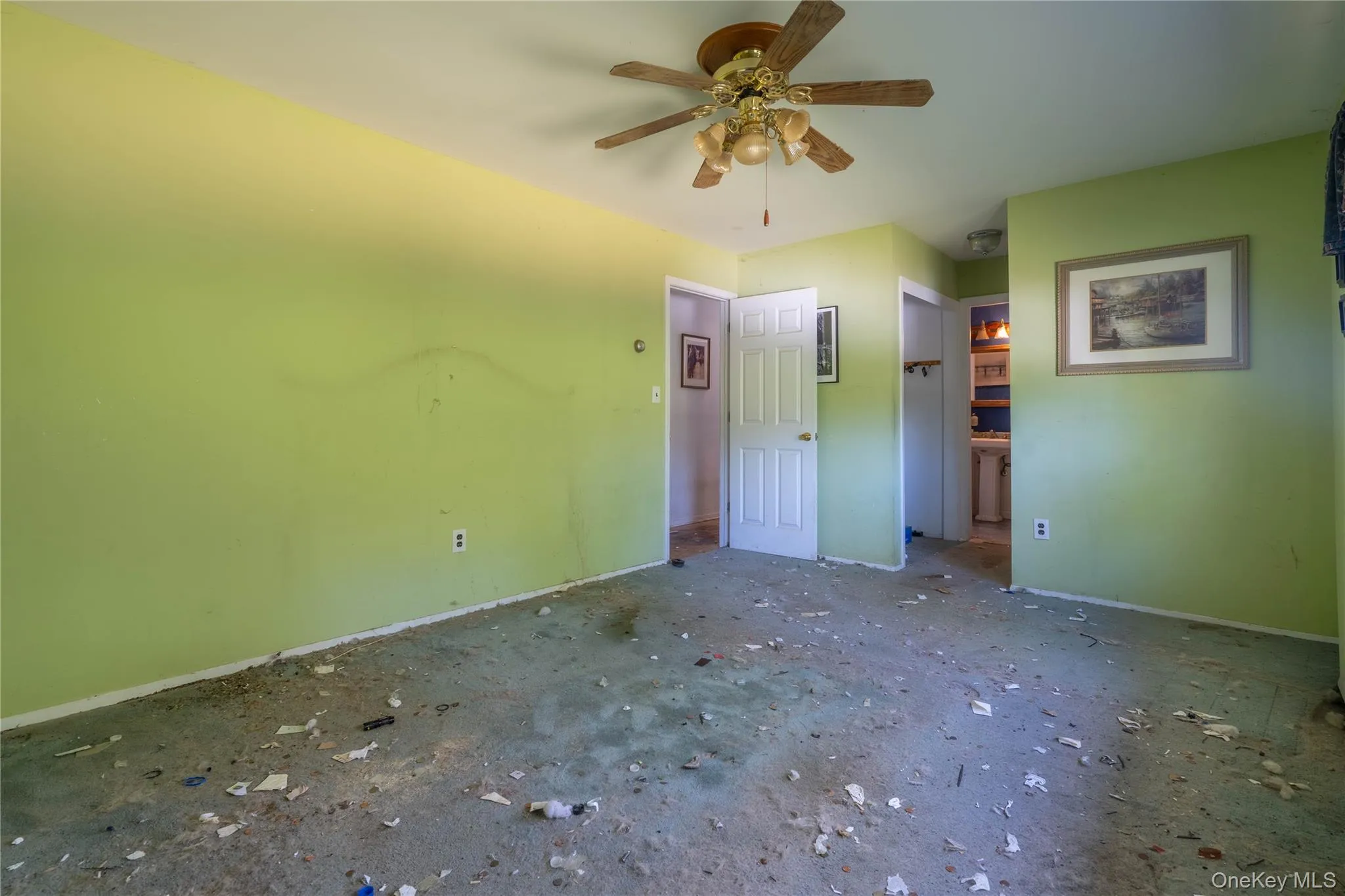 Room featuring a ceiling-mounted fan with integrated lighting and a white six-panel interior door Room featuring a ceiling-mounted fan with integrated lighting and a white six-panel interior door