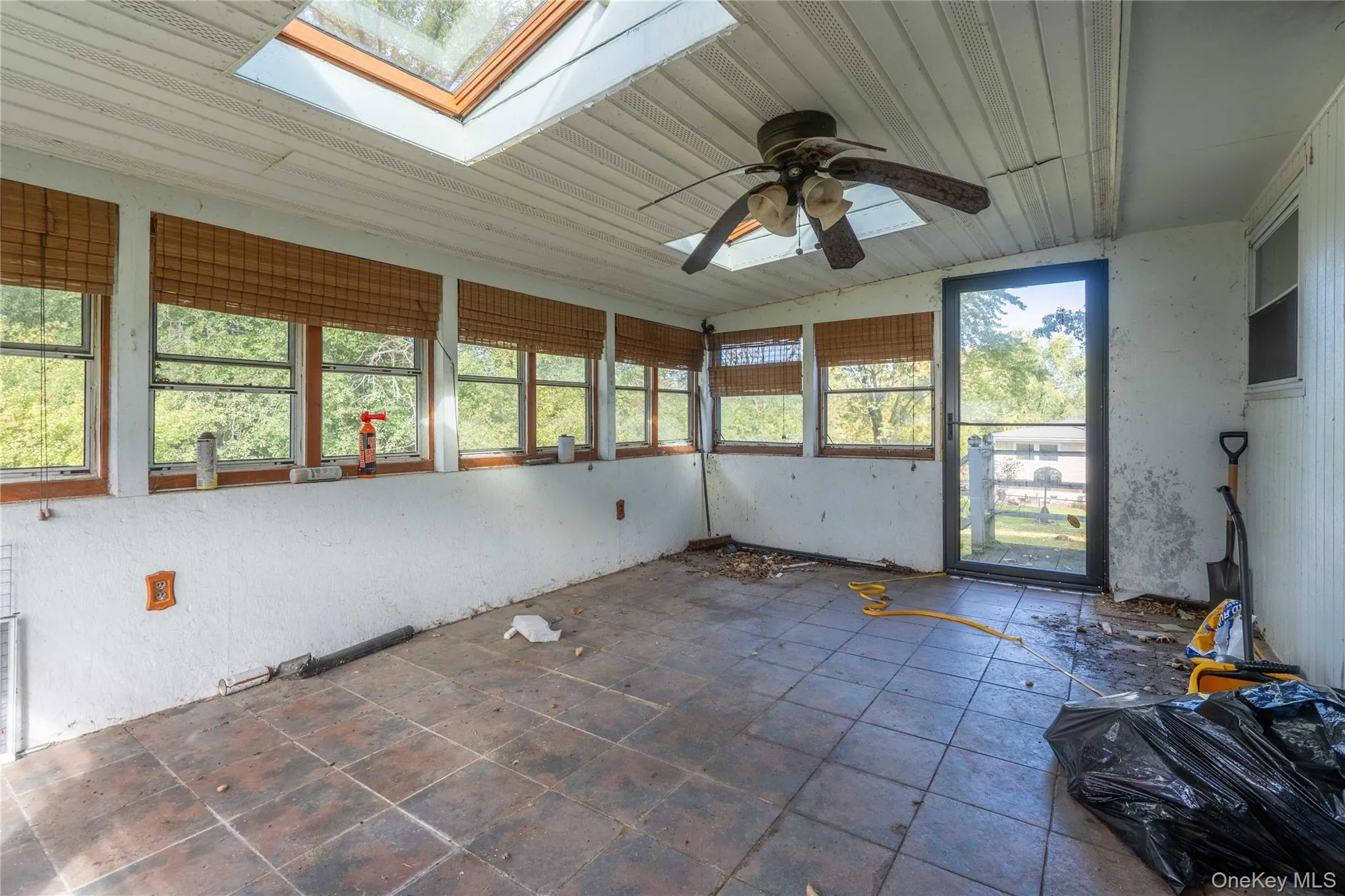 Enclosed porch featuring tile flooring, dual overhead skylights, multiple windows, and a ceiling fan Enclosed porch featuring tile flooring, dual overhead skylights, multiple windows, and a ceiling fan