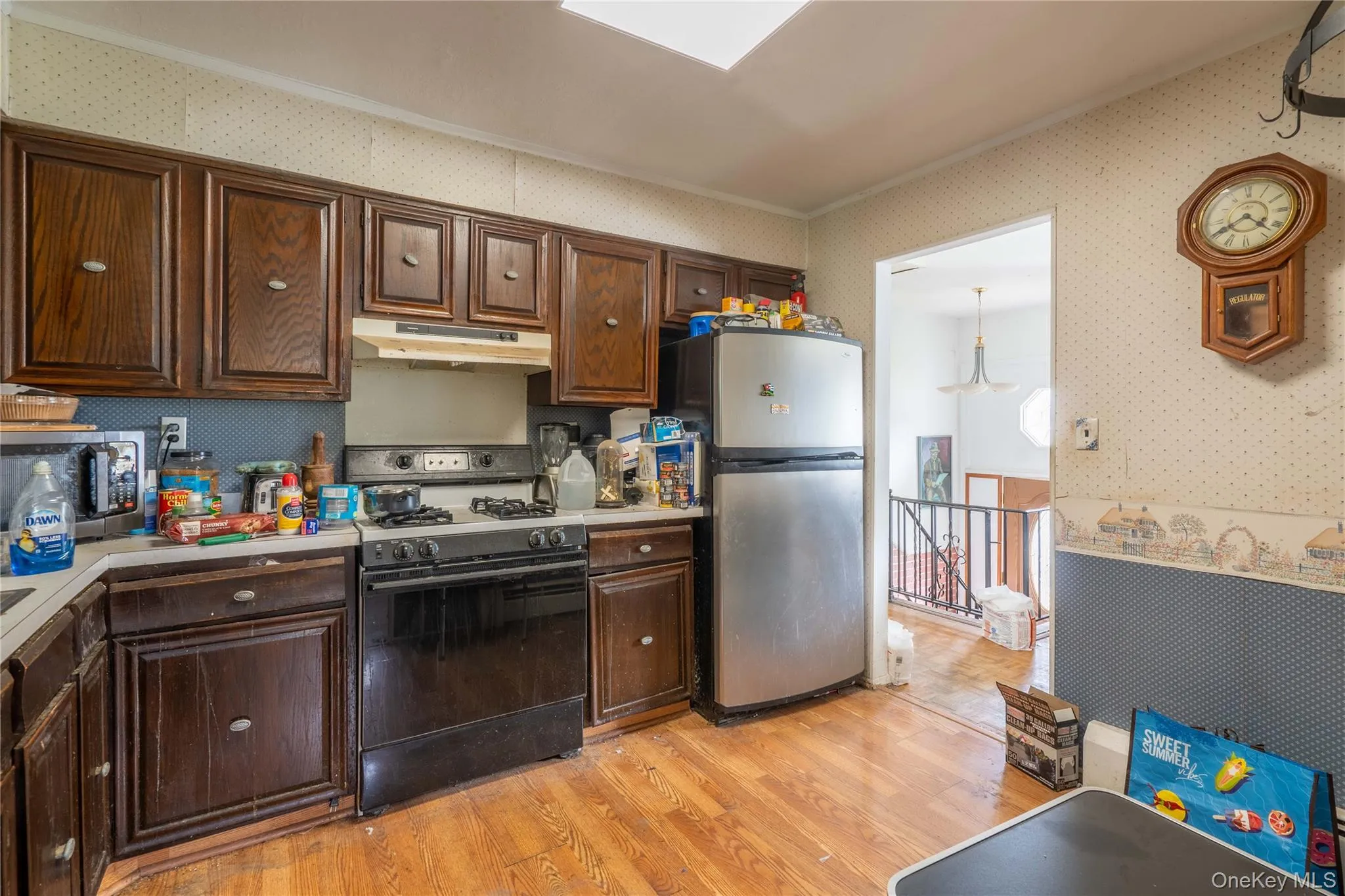 Kitchen featuring dark wood-finish cabinetry, stainless steel refrigerator, and wood-finish flooring Kitchen featuring dark wood-finish cabinetry, stainless steel refrigerator, and wood-finish flooring