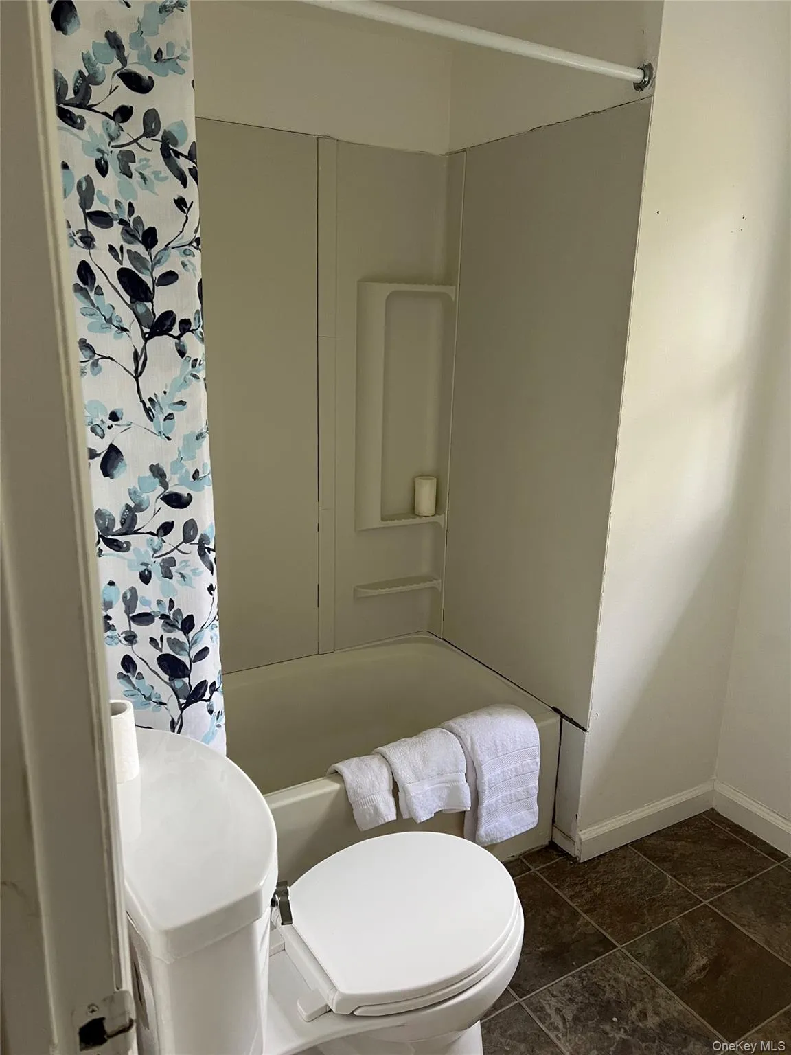 Bathroom with shower / tub combo with curtain and dark tile patterned floors Bathroom with shower / tub combo with curtain and dark tile patterned floors