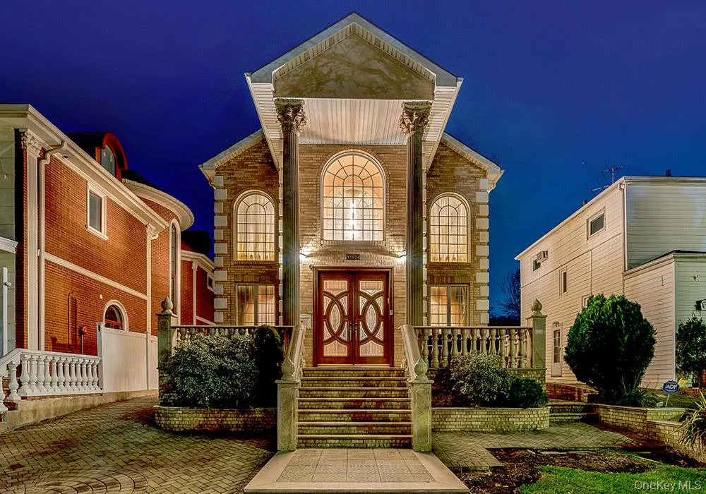Neoclassical architectural exterior featuring a pediment supported by dual Corinthian columns, arched windows, stone masonry, and a raised balustrade entry staircase Neoclassical architectural exterior featuring a pediment supported by dual Corinthian columns, arched windows, stone masonry, and a raised balustrade entry staircase