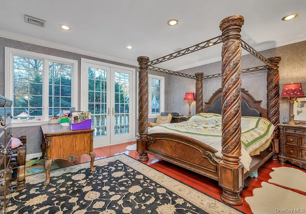 Room featuring cherry-finished hardwood flooring, crown molding, recessed lighting, and double glass-paned doors with exterior access Room featuring cherry-finished hardwood flooring, crown molding, recessed lighting, and double glass-paned doors with exterior access