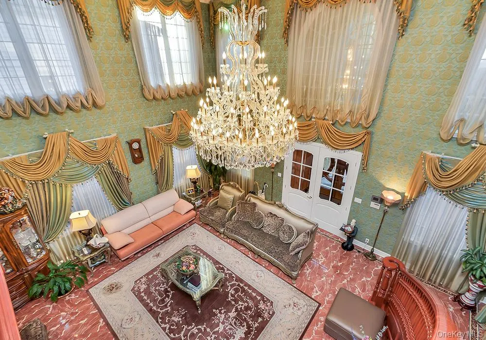 Grand foyer featuring high ceilings, ornate multi-tiered crystal chandelier, stone flooring, and arched double-entry doors Grand foyer featuring high ceilings, ornate multi-tiered crystal chandelier, stone flooring, and arched double-entry doors