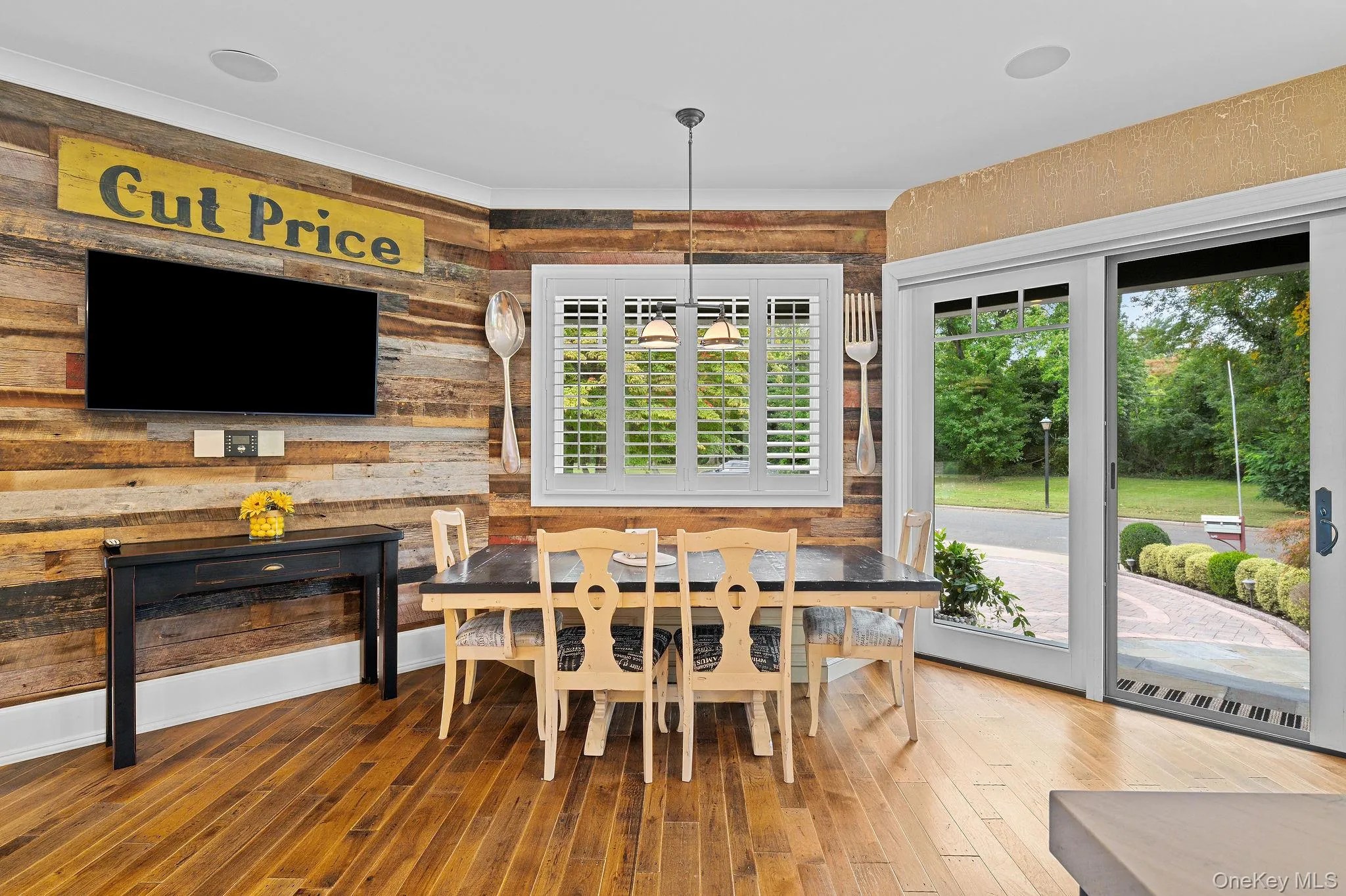 Reclaimed wood accent wall, wood-finish flooring, plantation shutters, and sliding glass doors with exterior access Reclaimed wood accent wall, wood-finish flooring, plantation shutters, and sliding glass doors with exterior access