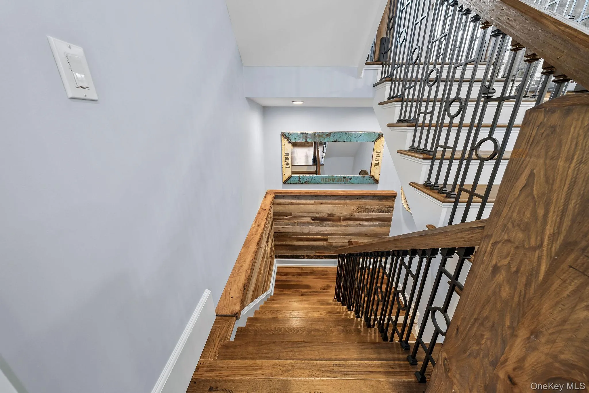Staircase featuring wood-finish treads, custom metal railings, and a horizontal wood-plank accent wall Staircase featuring wood-finish treads, custom metal railings, and a horizontal wood-plank accent wall