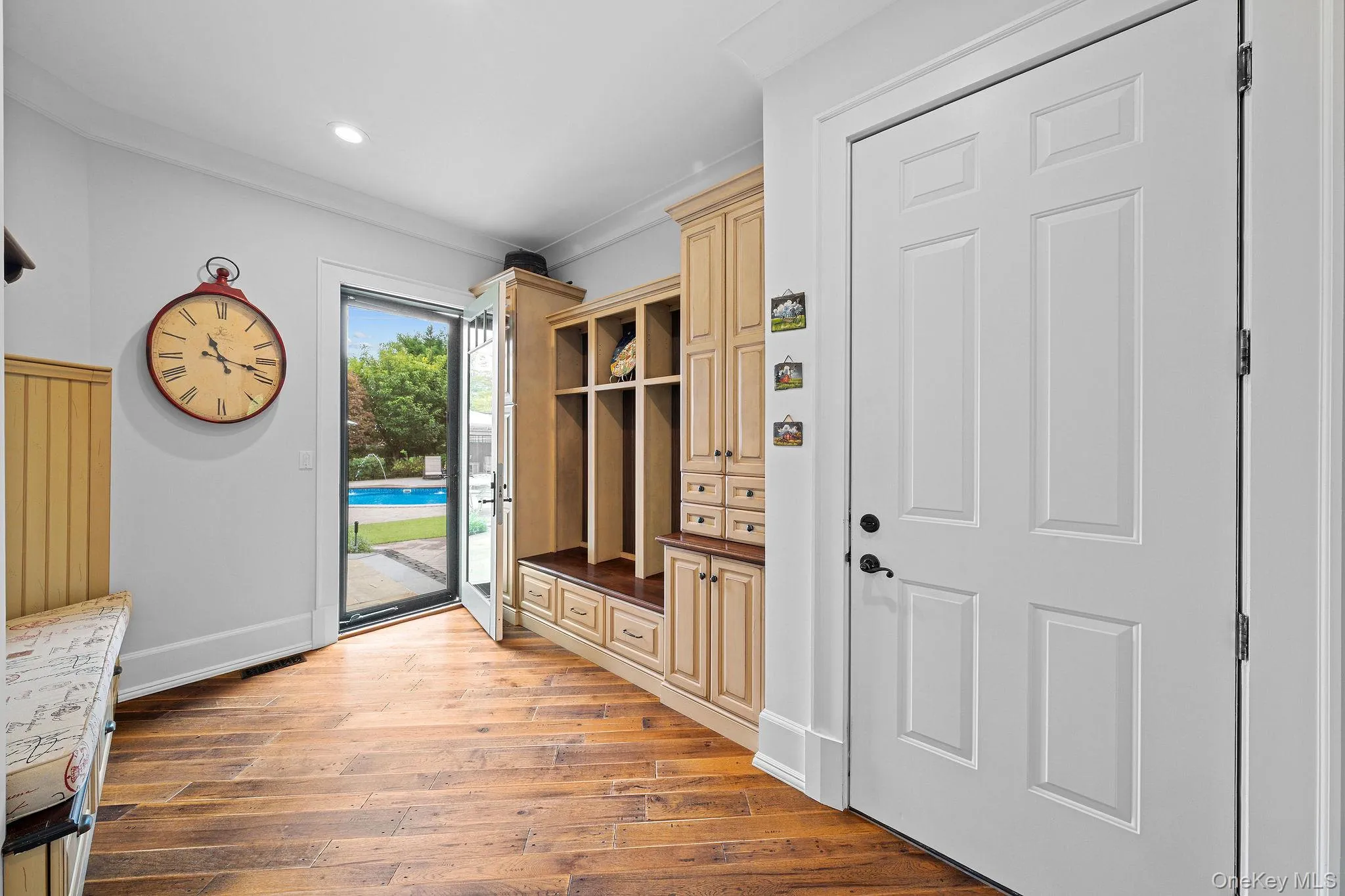 Entryway featuring wood-finish flooring, floor-to-ceiling custom built-in cabinetry, recessed lighting, and a glass-paneled exterior door Entryway featuring wood-finish flooring, floor-to-ceiling custom built-in cabinetry, recessed lighting, and a glass-paneled exterior door