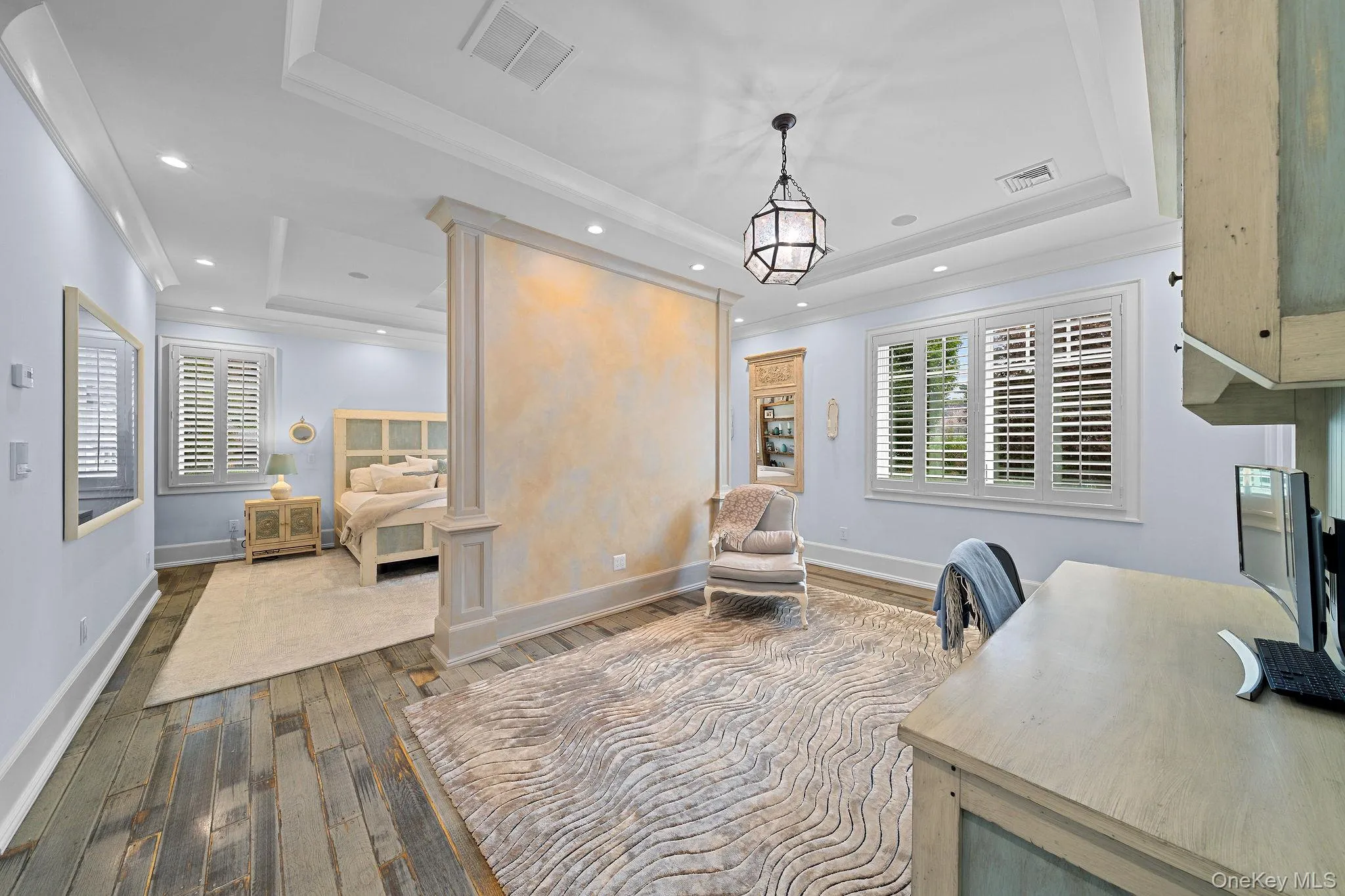 Tray ceilings with crown molding, custom partition wall with decorative finish, wood-finish flooring, recessed lighting, and plantation shutters Tray ceilings with crown molding, custom partition wall with decorative finish, wood-finish flooring, recessed lighting, and plantation shutters