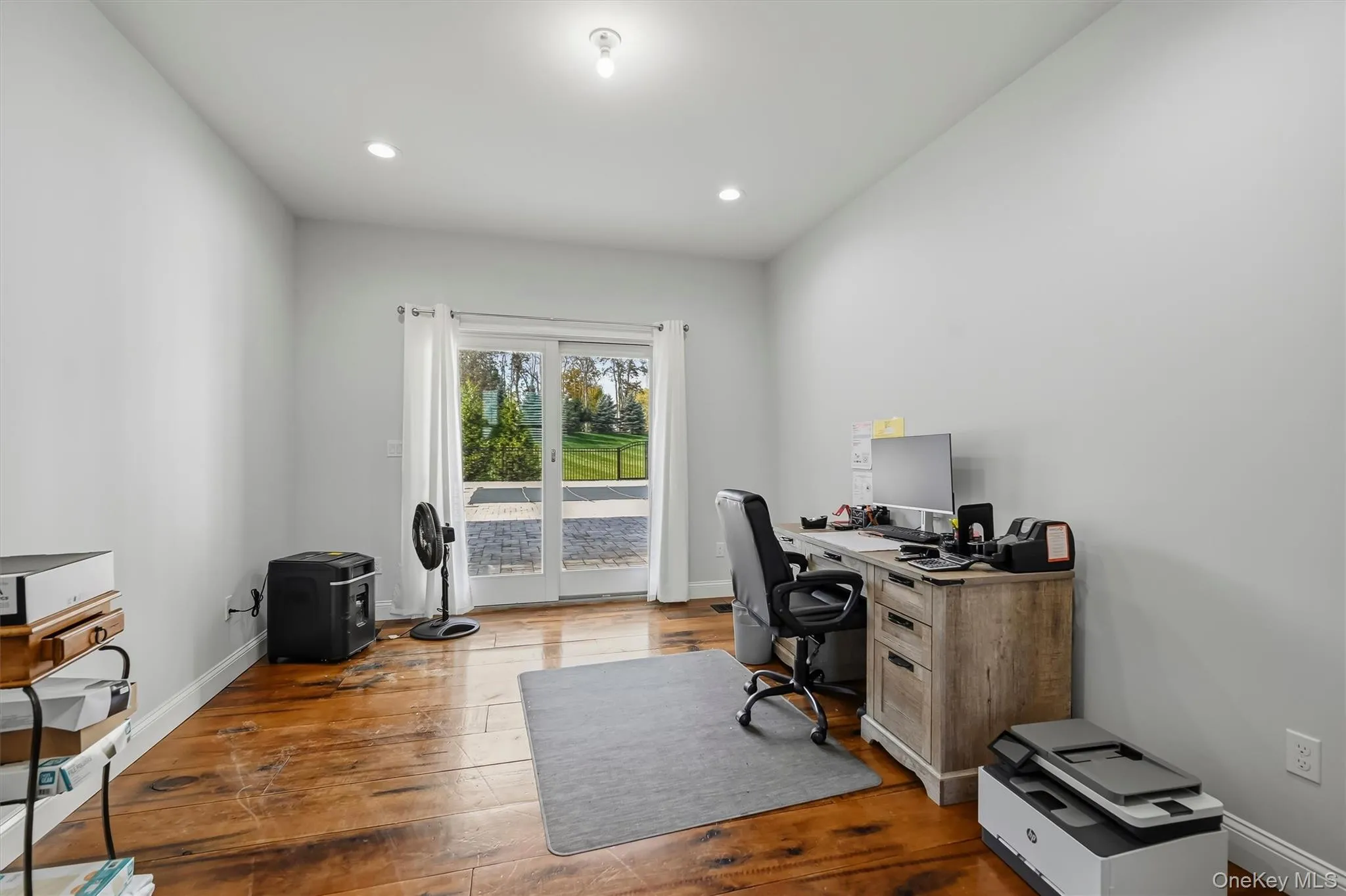 Room featuring wood-finish flooring, recessed lighting, and glass sliding doors to the patio Room featuring wood-finish flooring, recessed lighting, and glass sliding doors to the patio