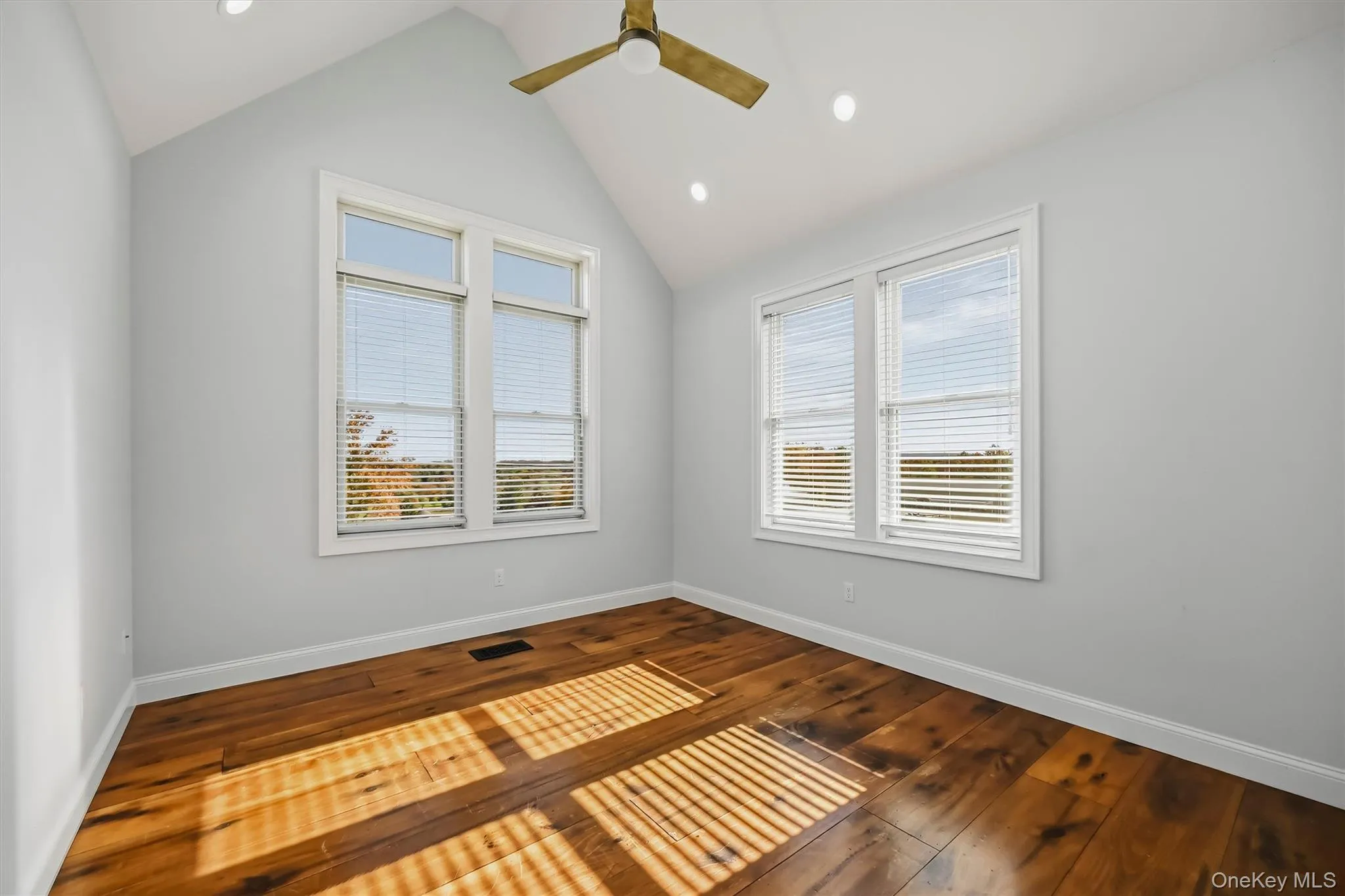 Vaulted ceiling with recessed lighting, wood-finish flooring, and expansive windows Vaulted ceiling with recessed lighting, wood-finish flooring, and expansive windows