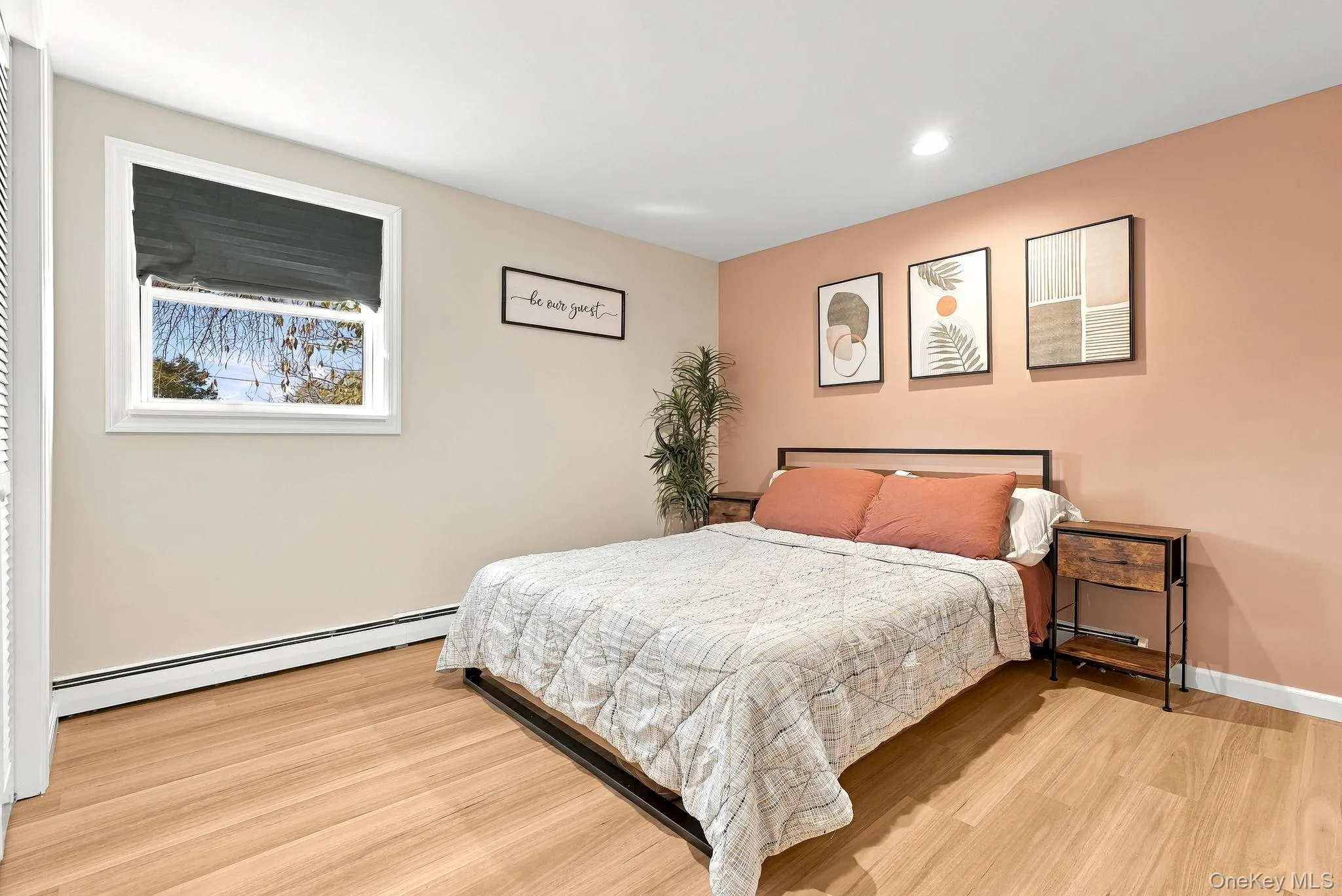 Bedroom featuring wood-finish flooring, a neutral color palette with an accent wall, and recessed ceiling lighting Bedroom featuring wood-finish flooring, a neutral color palette with an accent wall, and recessed ceiling lighting
