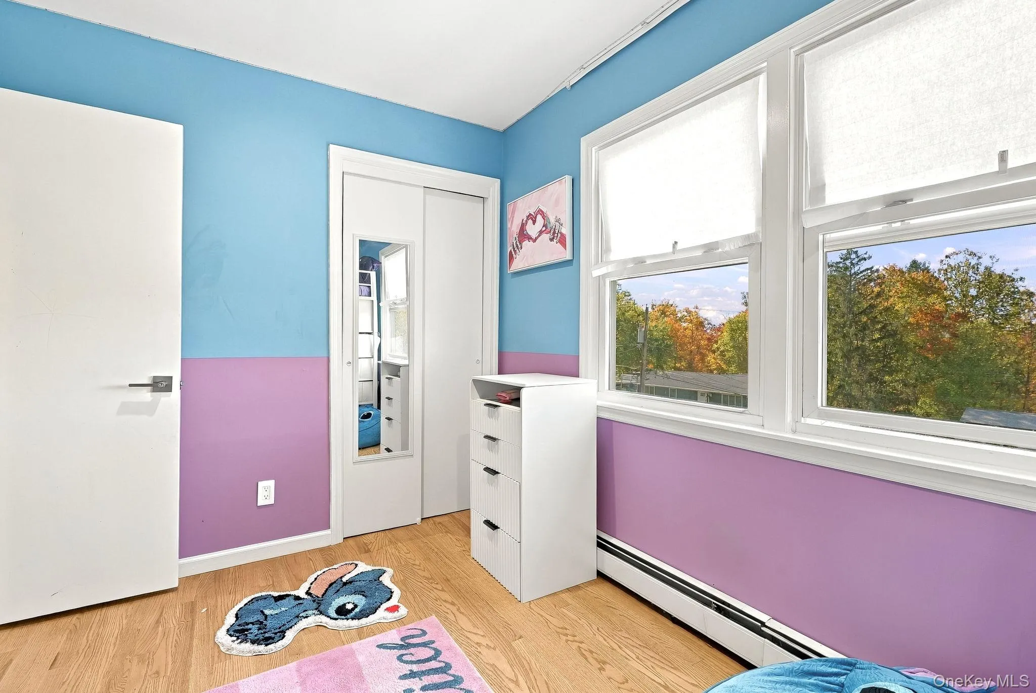 Wood-finish flooring, dual-panel sliding closet doors with an inset mirror, and double-hung windows Wood-finish flooring, dual-panel sliding closet doors with an inset mirror, and double-hung windows