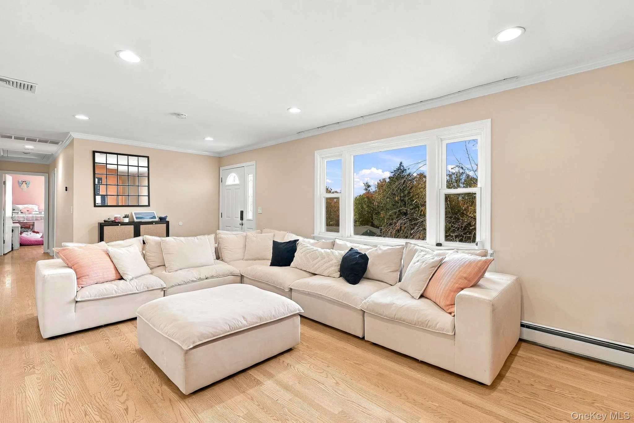 Living area featuring light-toned wood-finish flooring, recessed lighting, and a large multi-pane window Living area featuring light-toned wood-finish flooring, recessed lighting, and a large multi-pane window