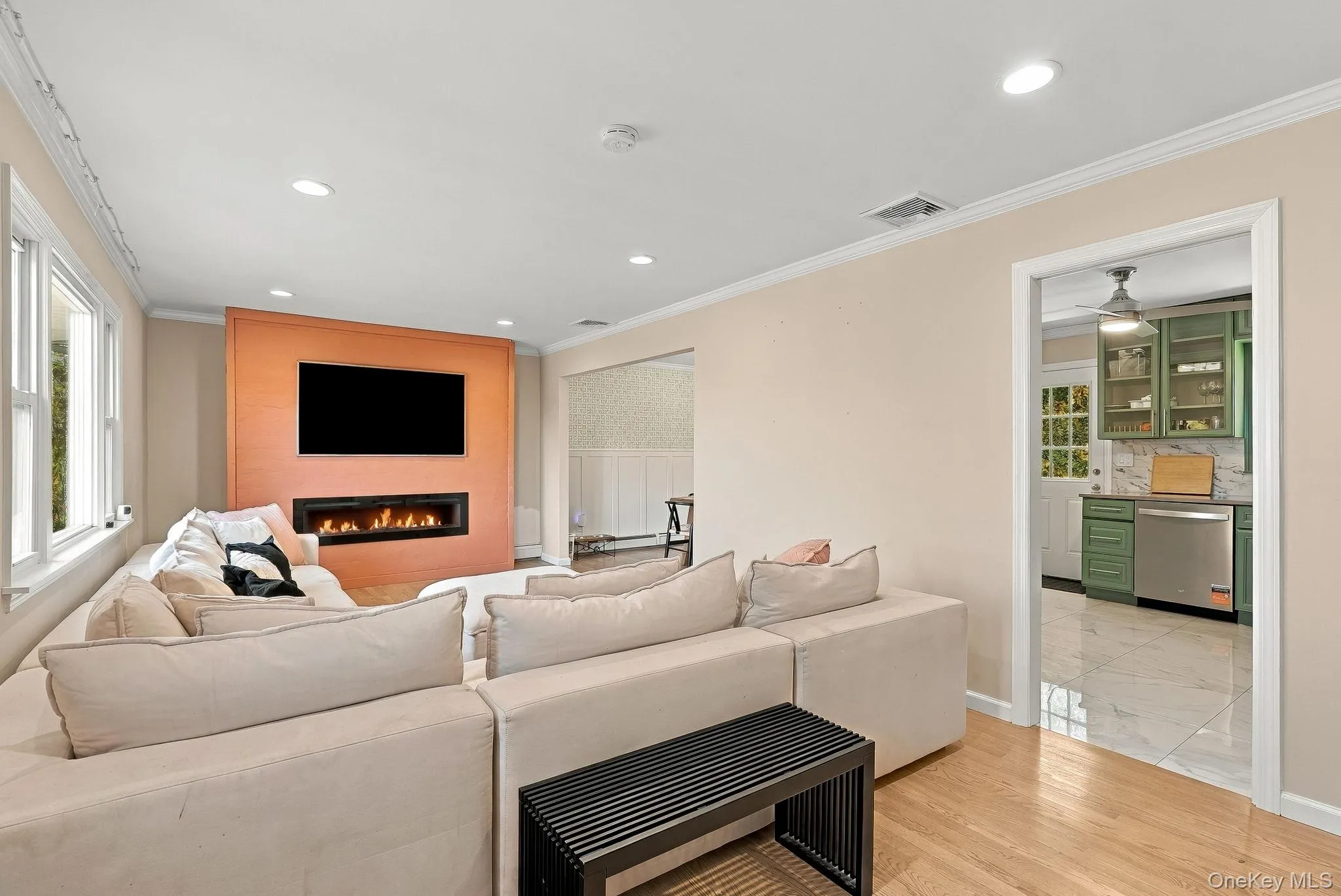 Living space featuring a linear electric fireplace, wood-finish flooring, recessed lighting, and crown molding Living space featuring a linear electric fireplace, wood-finish flooring, recessed lighting, and crown molding