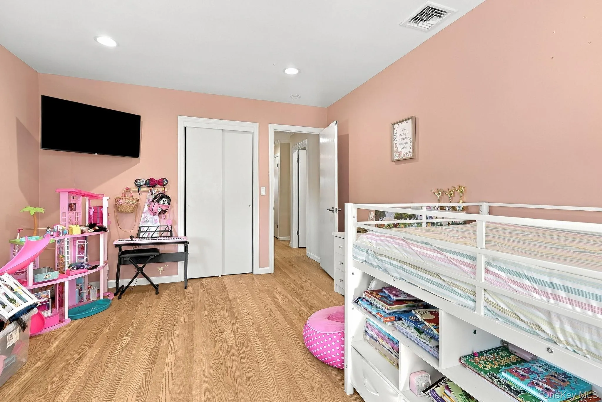 Room featuring wood-finish flooring, recessed lighting, and a sliding-door closet Room featuring wood-finish flooring, recessed lighting, and a sliding-door closet