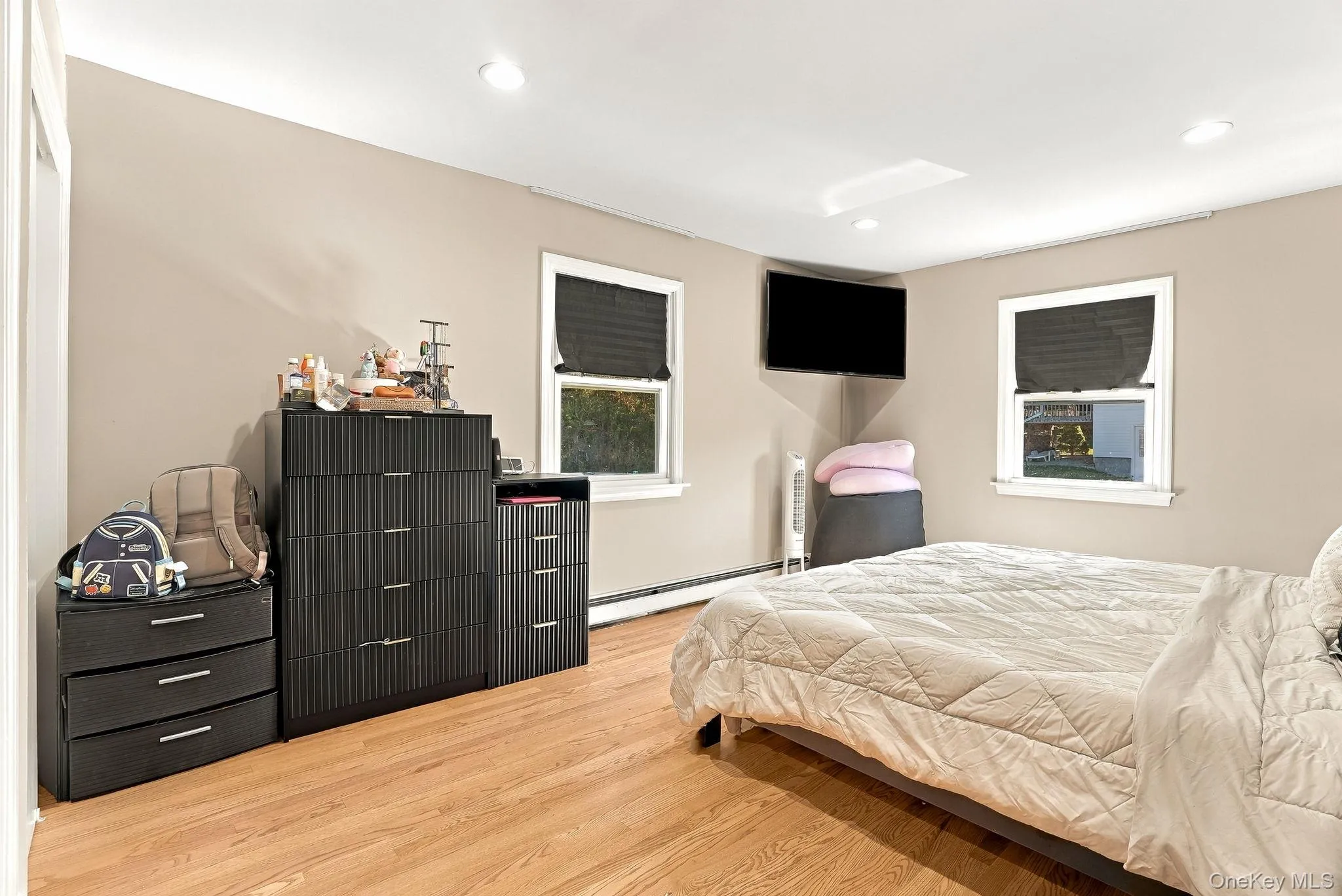Room featuring wood-finish flooring, recessed lighting, and two windows with black window treatments Room featuring wood-finish flooring, recessed lighting, and two windows with black window treatments