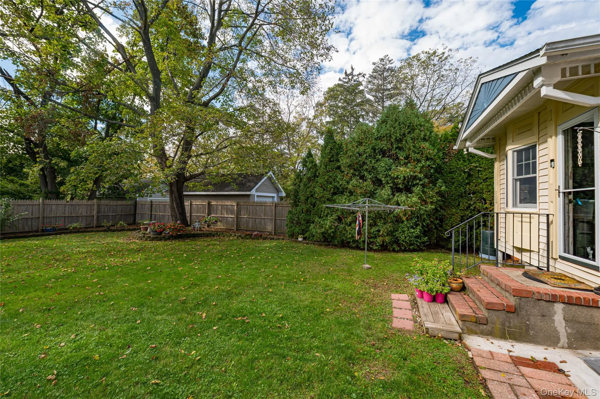 Private backyard featuring a level lawn, mature trees, wood privacy fencing, and a brick-stepped entrance Private backyard featuring a level lawn, mature trees, wood privacy fencing, and a brick-stepped entrance