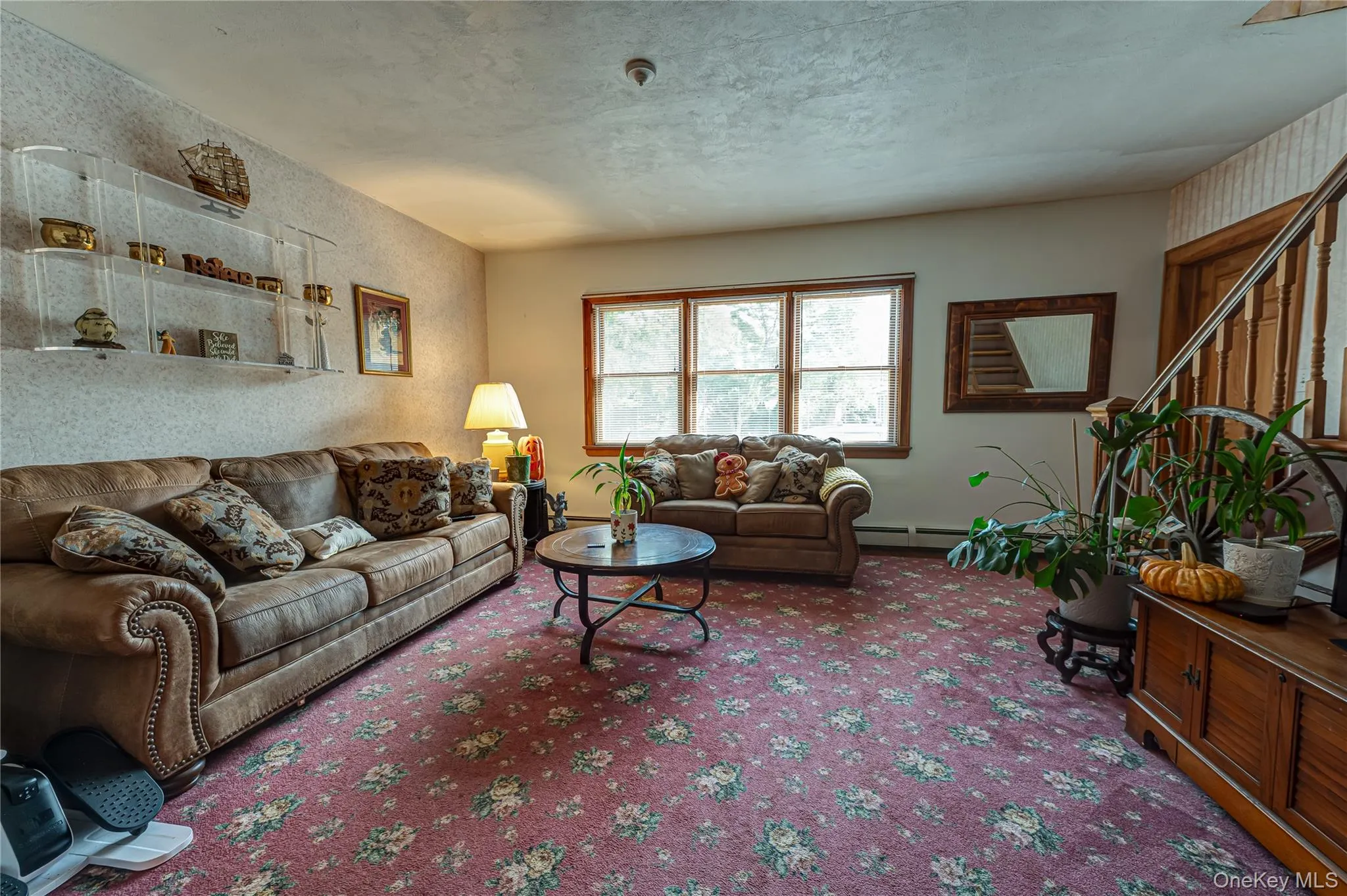 Sun-filled Living area featuring a large window, a wooden staircase with decorative balusters and hardwood floors. Sun-filled Living area featuring a large window, a wooden staircase with decorative balusters and hardwood floors.