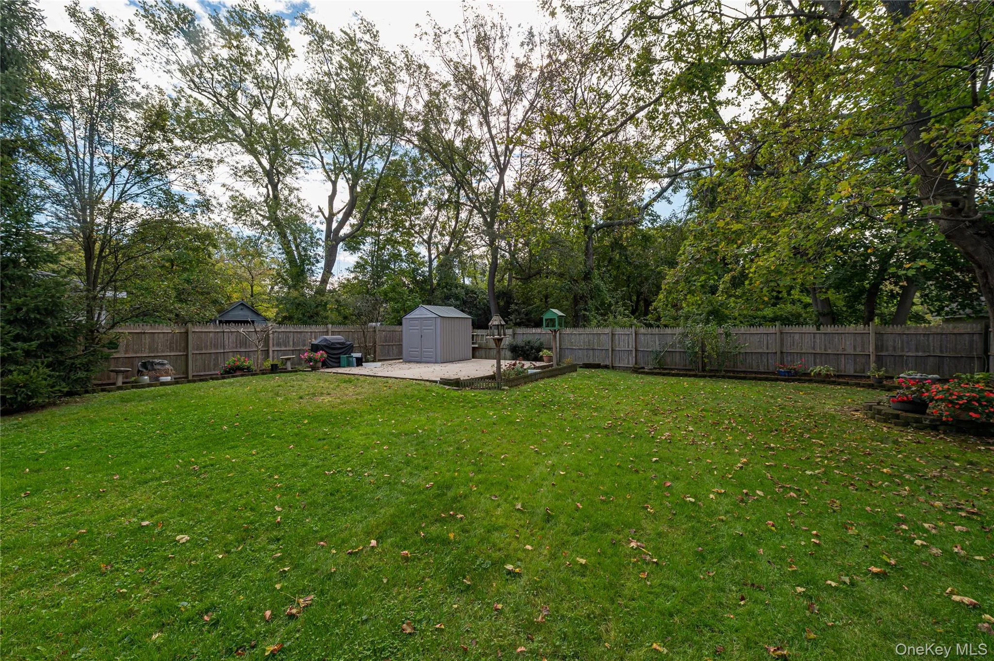 Expansive backyard featuring a level lawn, mature trees, wood privacy fencing, a cement patio area large enough to accommodate a 2 car garage and built-in landscape bordering Expansive backyard featuring a level lawn, mature trees, wood privacy fencing, a cement patio area large enough to accommodate a 2 car garage and built-in landscape bordering