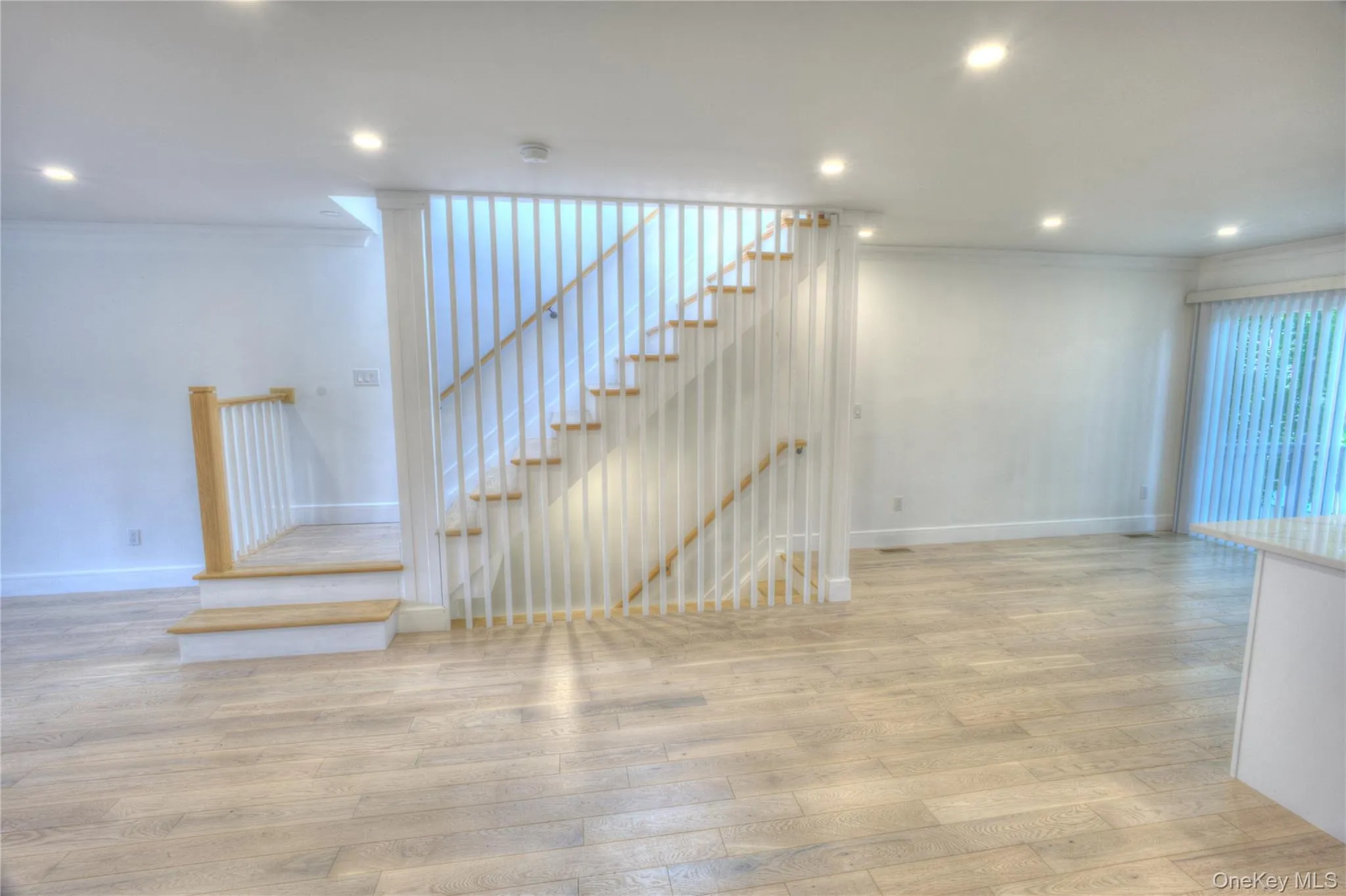 Staircase featuring white vertical spindles, natural wood-finish treads, and recessed lighting throughout Staircase featuring white vertical spindles, natural wood-finish treads, and recessed lighting throughout