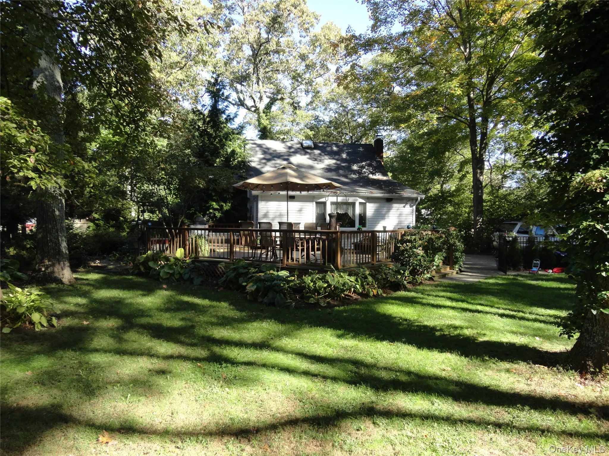Expansive backyard featuring a tiered wood deck, mature trees, manicured lawn, and lush landscaping Expansive backyard featuring a tiered wood deck, mature trees, manicured lawn, and lush landscaping