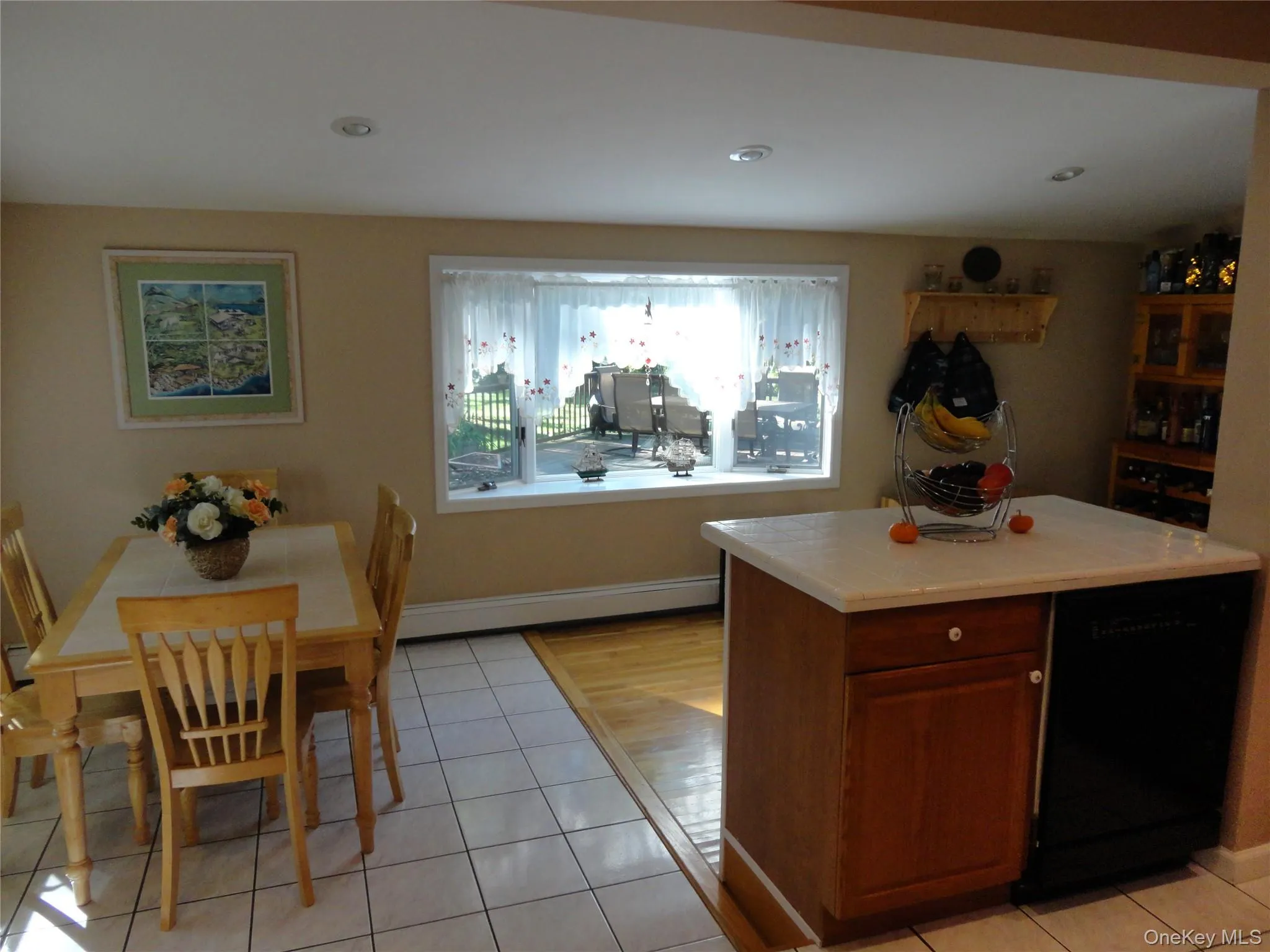 Kitchen featuring an island with tile countertop, wood-finish cabinetry, recessed lighting, tile flooring, and a large picture window Kitchen featuring an island with tile countertop, wood-finish cabinetry, recessed lighting, tile flooring, and a large picture window