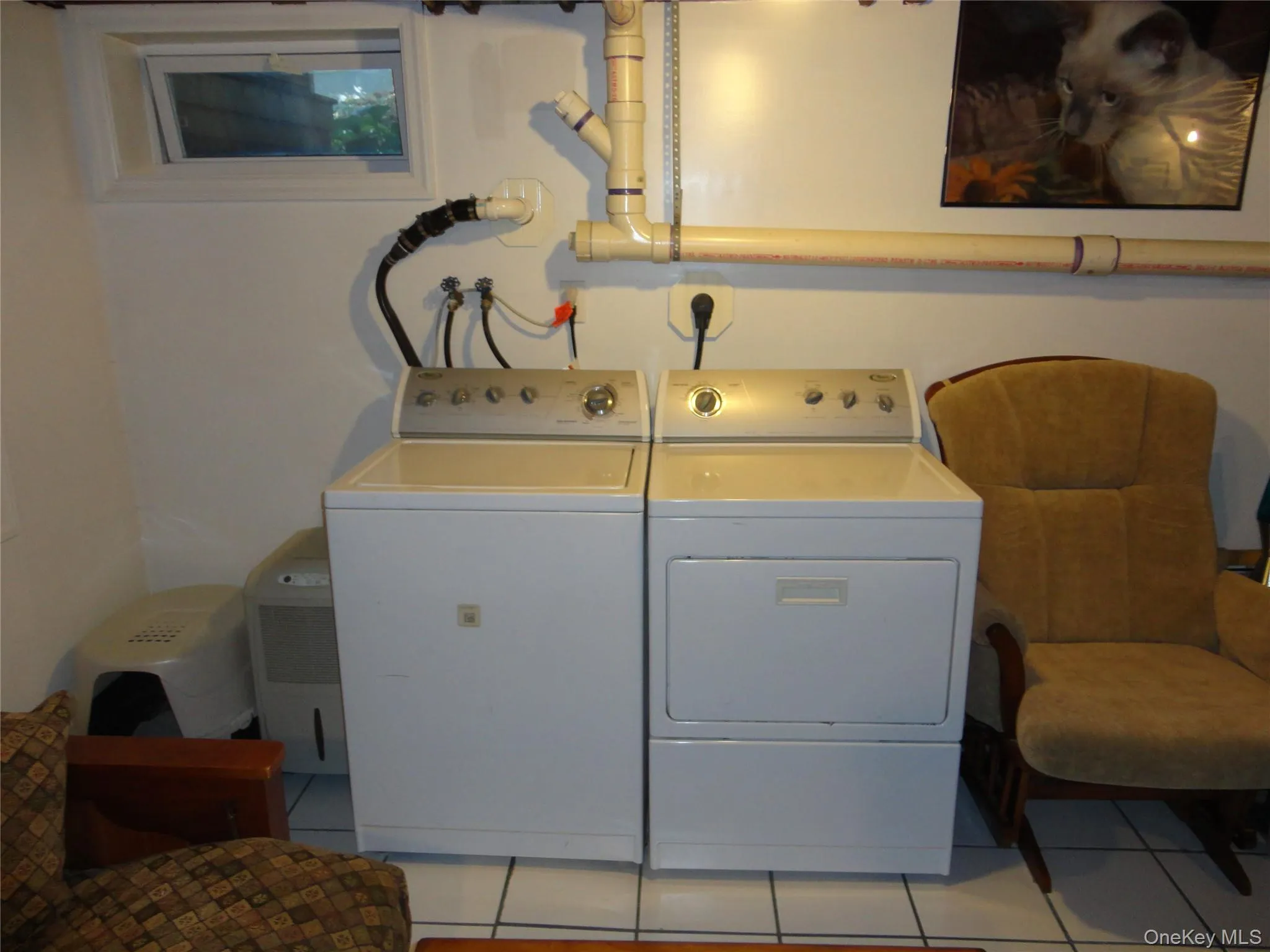 Laundry area featuring white ceramic tile flooring and a hopper-style window Laundry area featuring white ceramic tile flooring and a hopper-style window
