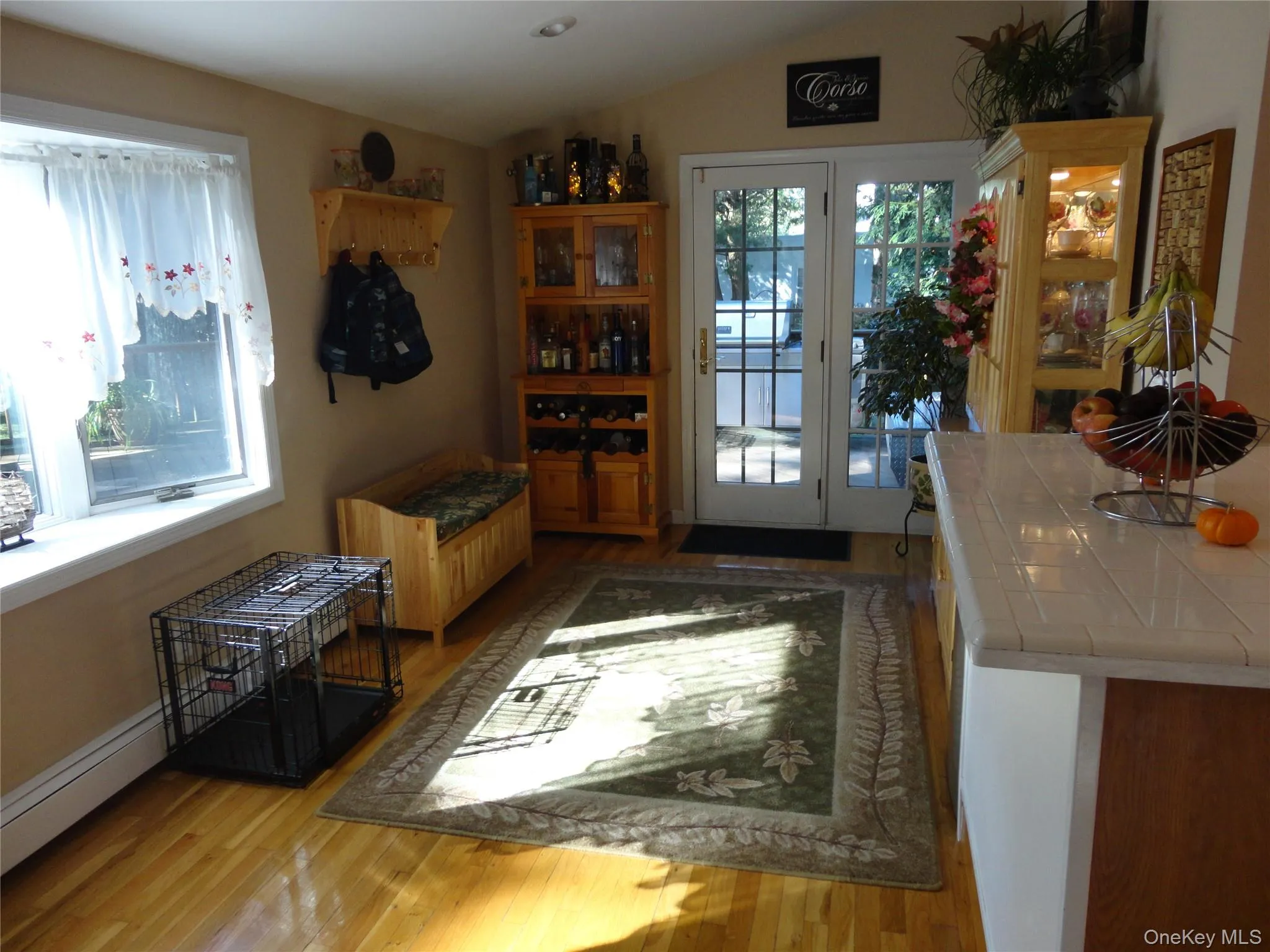Light-filled interior featuring wood-finish flooring, a vaulted ceiling, and glass-paneled double doors leading to the exterior Light-filled interior featuring wood-finish flooring, a vaulted ceiling, and glass-paneled double doors leading to the exterior