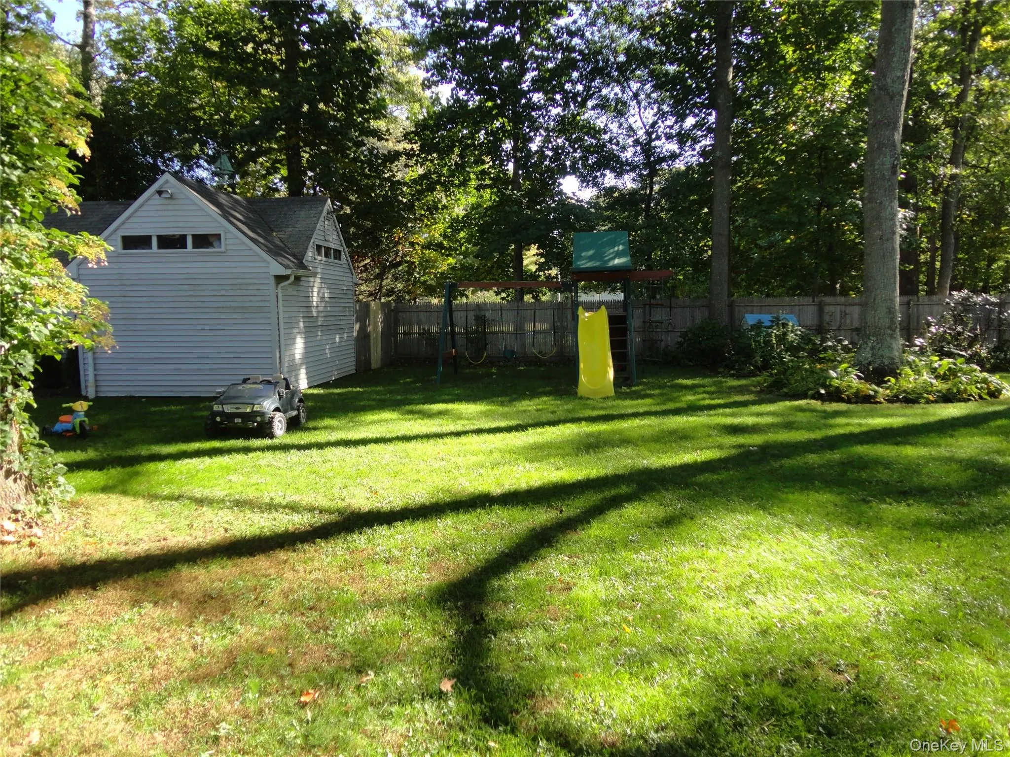 Spacious backyard featuring a manicured lawn, perimeter wood fencing, and mature trees Spacious backyard featuring a manicured lawn, perimeter wood fencing, and mature trees