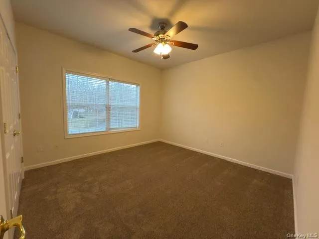 Unfurnished room featuring dark carpet and a ceiling fan Unfurnished room featuring dark carpet and a ceiling fan