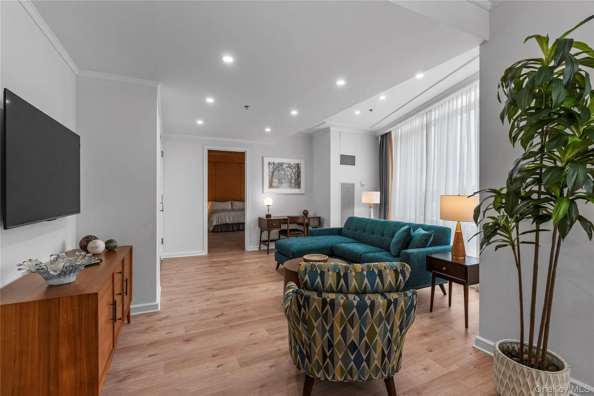 Living room with crown molding, light wood finished floors, recessed lighting, visible vents, and baseboards Living room with crown molding, light wood finished floors, recessed lighting, visible vents, and baseboards