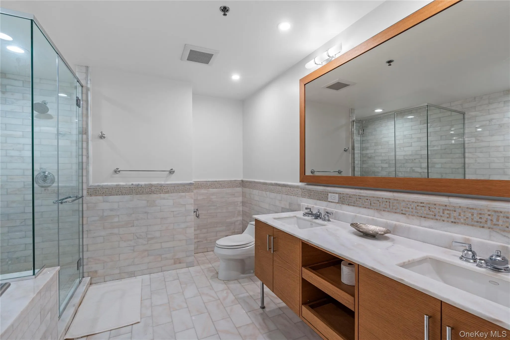 Bathroom with tile walls, visible vents, a sink, and a shower stall Bathroom with tile walls, visible vents, a sink, and a shower stall