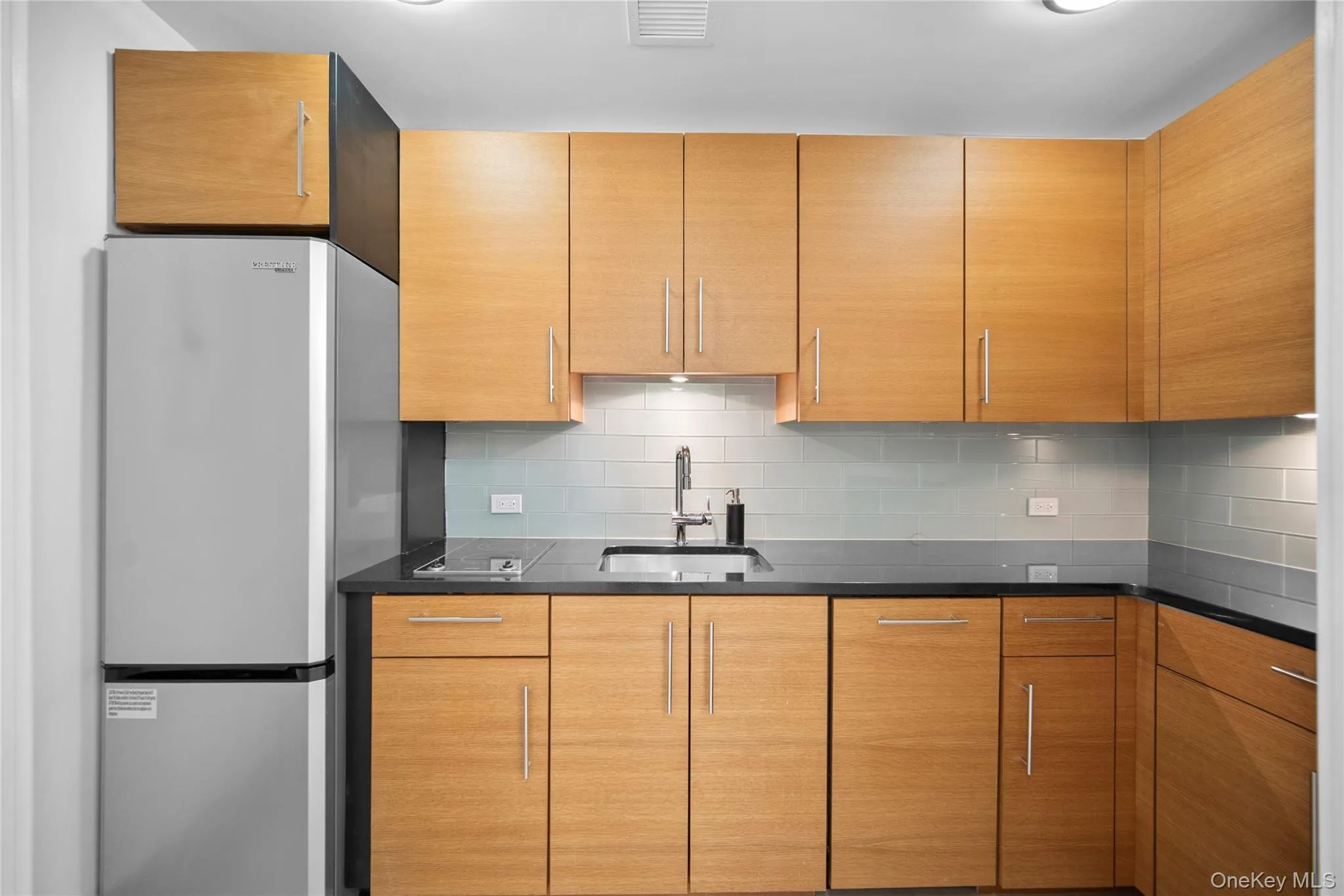 Kitchen with freestanding refrigerator, a sink, and tasteful backsplash Kitchen with freestanding refrigerator, a sink, and tasteful backsplash