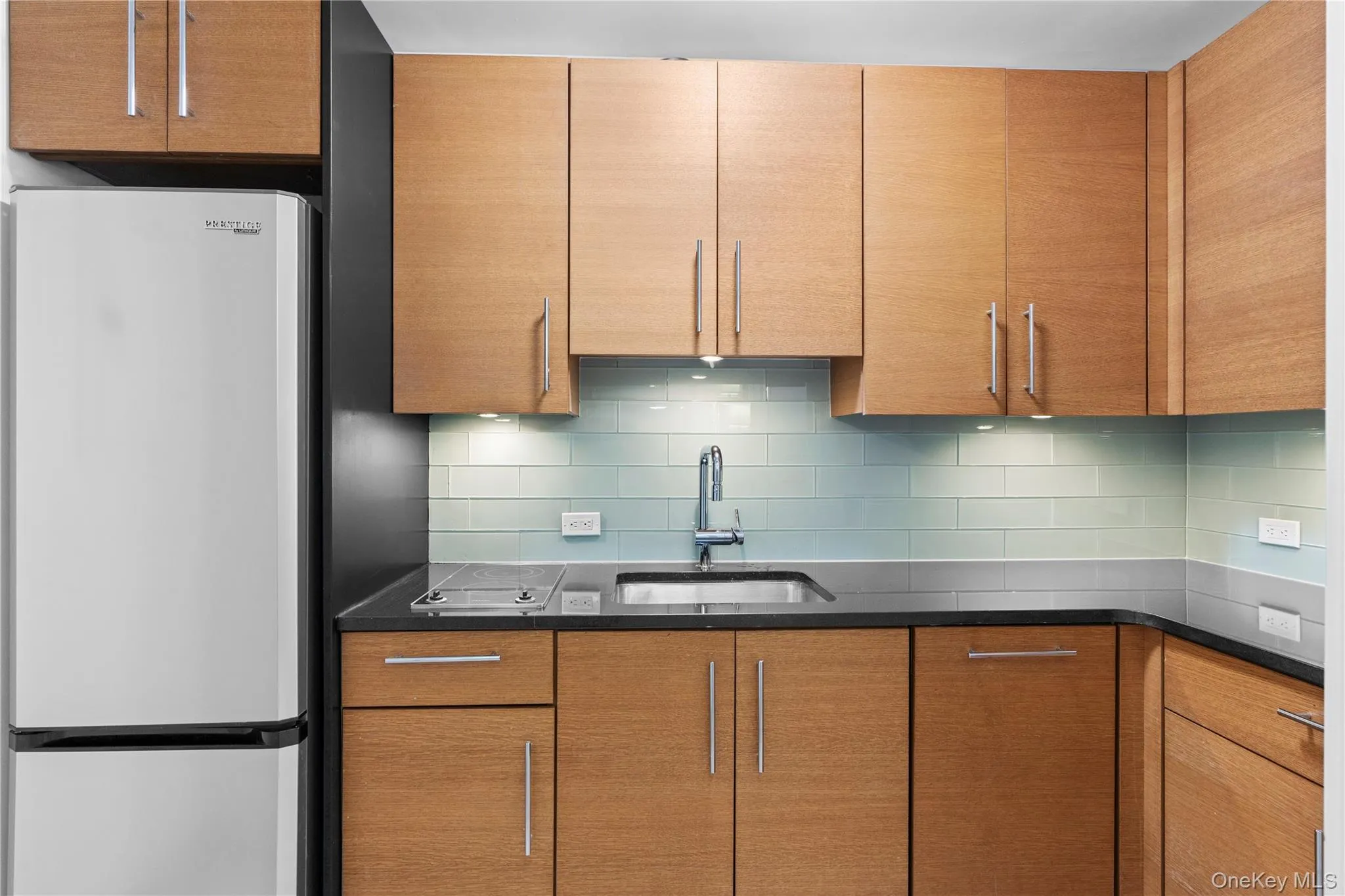 Kitchen with freestanding refrigerator, a sink, and backsplash Kitchen with freestanding refrigerator, a sink, and backsplash