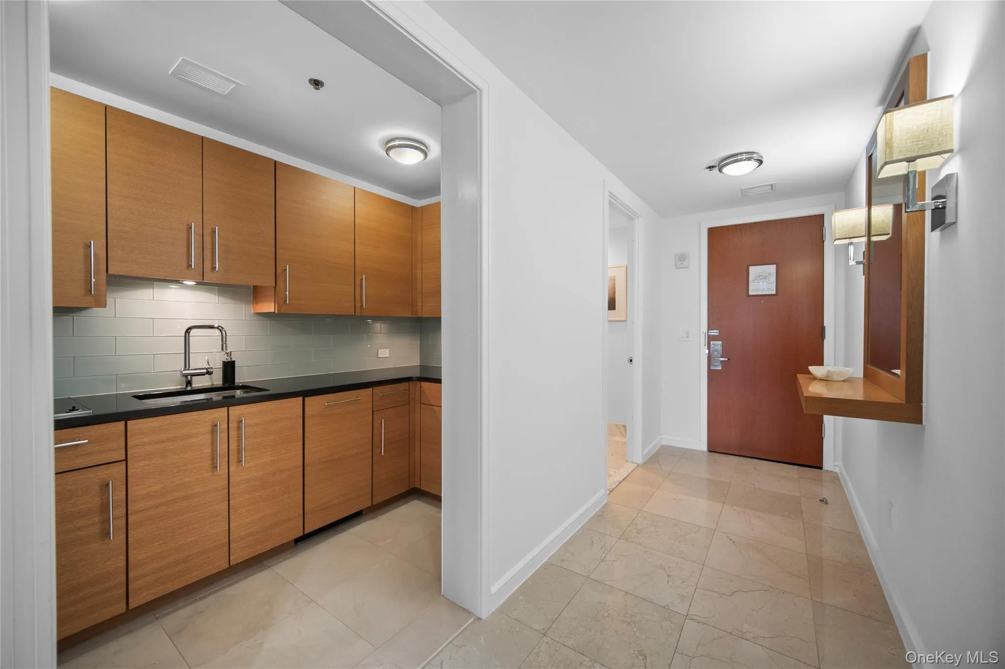 Kitchen featuring a sink, baseboards, brown cabinets, dark countertops, and decorative backsplash Kitchen featuring a sink, baseboards, brown cabinets, dark countertops, and decorative backsplash