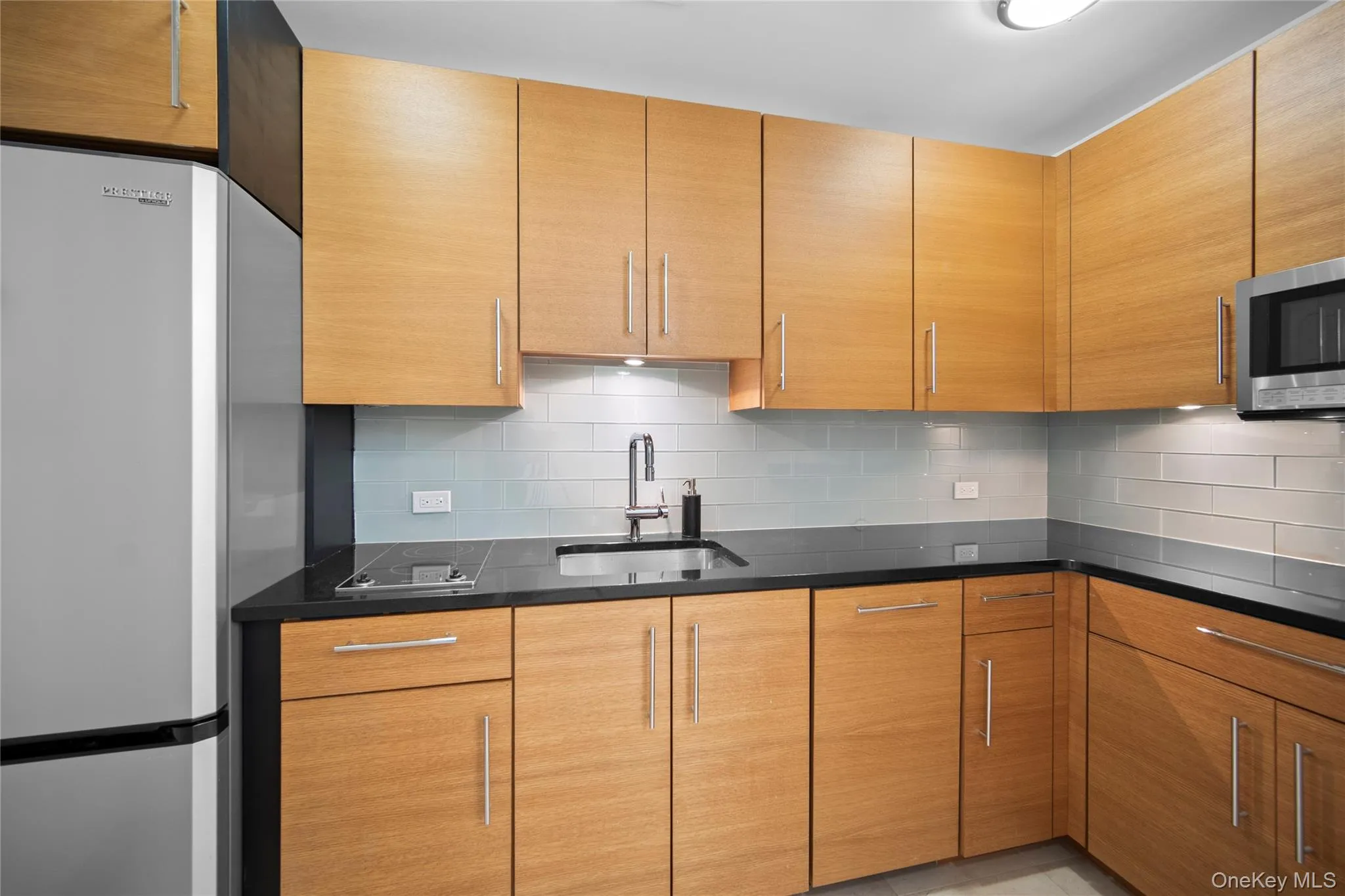 Kitchen featuring appliances with stainless steel finishes, a sink, tasteful backsplash, and dark stone counters Kitchen featuring appliances with stainless steel finishes, a sink, tasteful backsplash, and dark stone counters