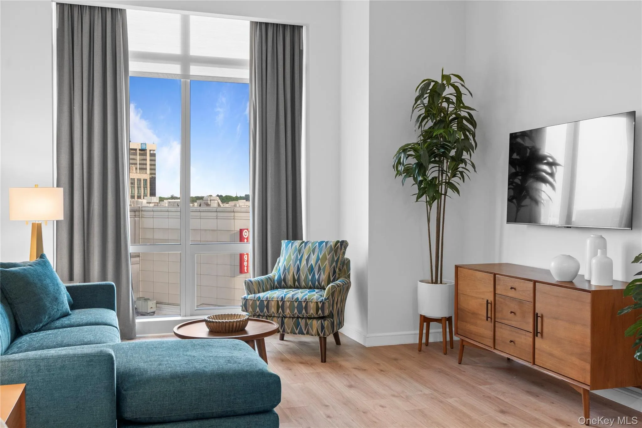 Sitting room featuring light wood-style floors, plenty of natural light, and baseboards Sitting room featuring light wood-style floors, plenty of natural light, and baseboards