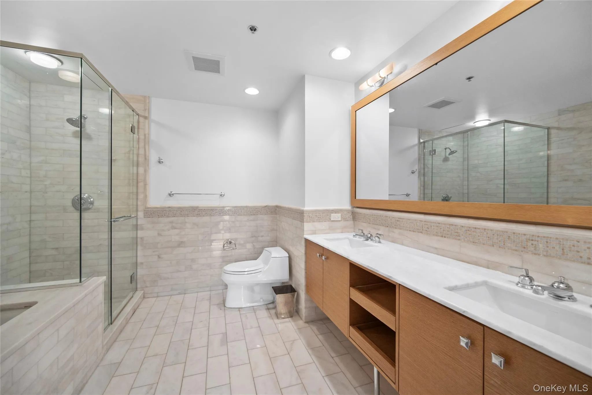 Bathroom featuring tile walls, double vanity, a stall shower, toilet, and a bathtub Bathroom featuring tile walls, double vanity, a stall shower, toilet, and a bathtub