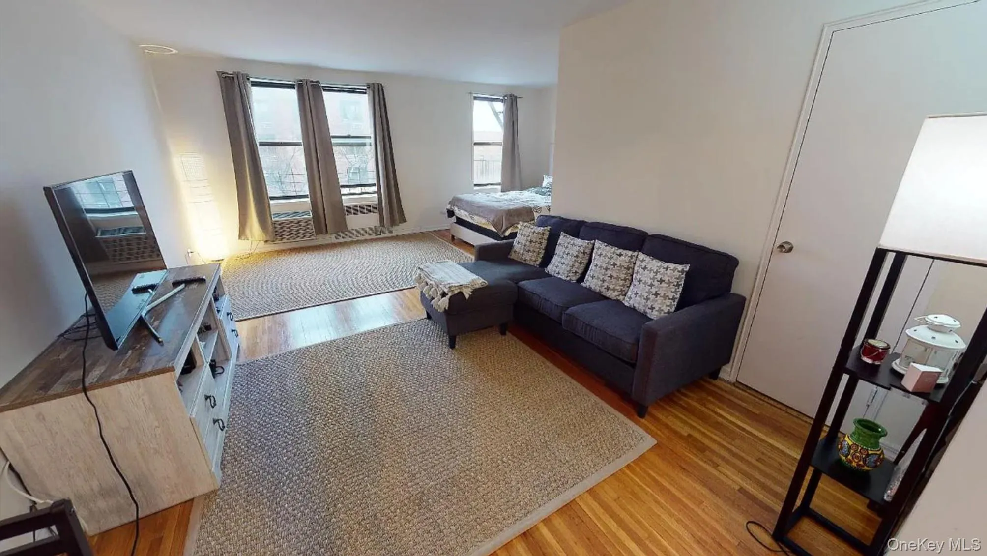 Open-concept interior featuring wood-finish flooring, multi-pane windows, and a reach-in closet with a panel door Open-concept interior featuring wood-finish flooring, multi-pane windows, and a reach-in closet with a panel door