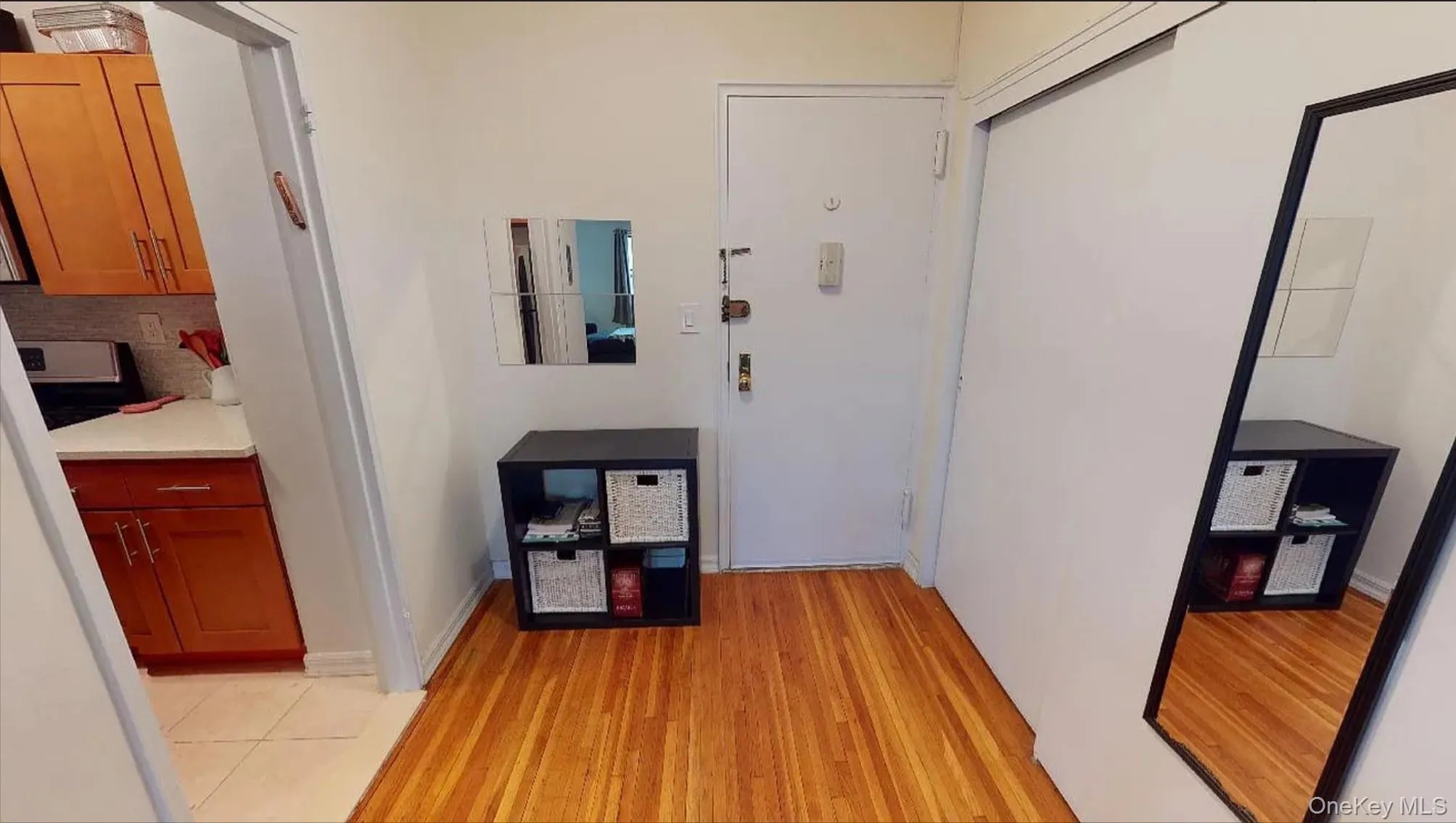 Entryway featuring wood-finish flooring, a wall-mounted mirrored accent, and a built-in sliding door closet Entryway featuring wood-finish flooring, a wall-mounted mirrored accent, and a built-in sliding door closet