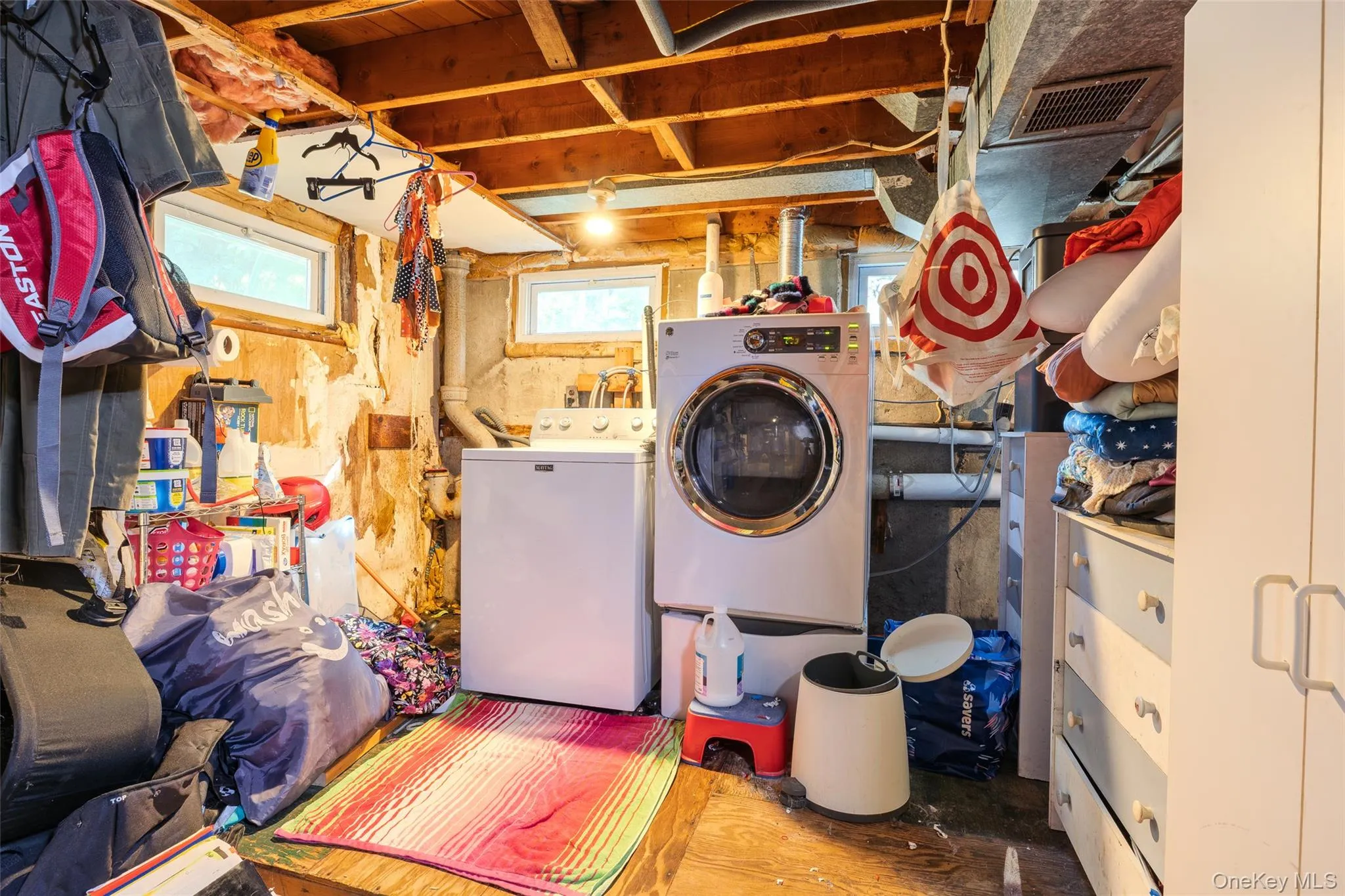 Utility area featuring exposed ceiling joists, masonry foundation walls, multiple horizontal windows, and laundry hookups Utility area featuring exposed ceiling joists, masonry foundation walls, multiple horizontal windows, and laundry hookups