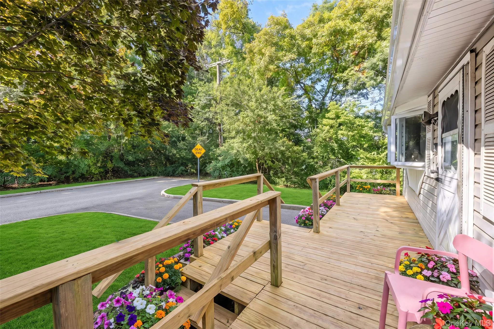 Wrap-around wood decking featuring custom-built wooden railings and integrated landscape flower beds Wrap-around wood decking featuring custom-built wooden railings and integrated landscape flower beds